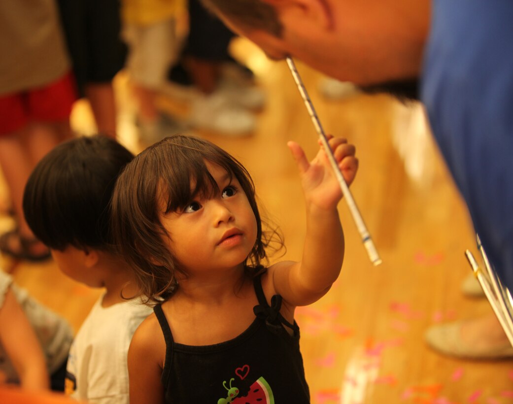 A military child eagerly reaches for a magically appearing magic wand from magician Jeff Jones’ as part of the grand finale of the summer reading program at Marston Pavilion aboard Marine Corps Base Camp Lejeune Aug. 3. Every child at the finale received a magic wand after being dazzled by disappearing birds, magic candy machines and even a rat.