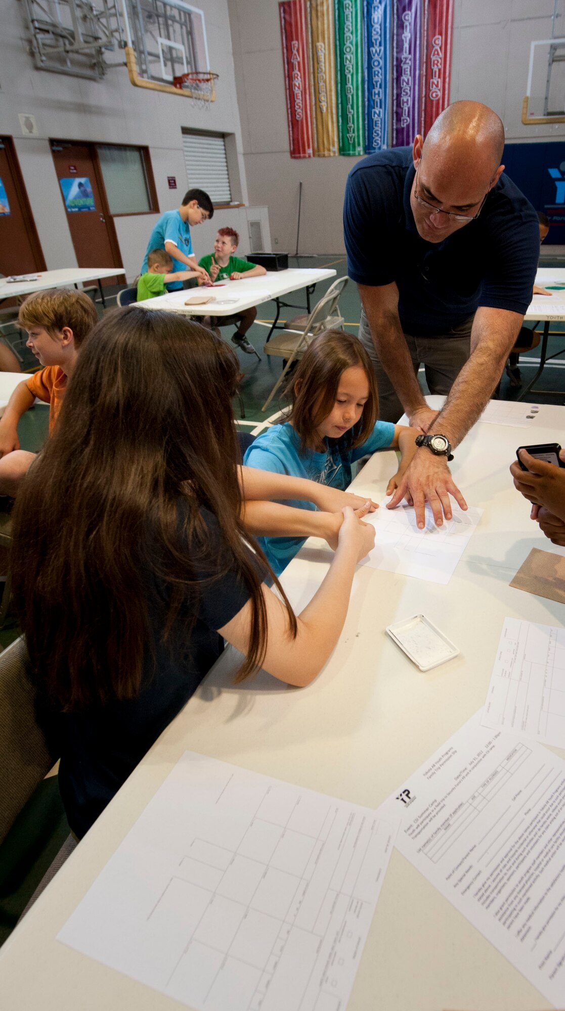 YOKOTA AIR BASE, Japan -- Investigator Thomas Bonte, 374th Security Forces Squadron, helps the youth attending the crime scene investigation camp practice fingerprinting at the Youth Center at Yokota Air Base, Japan, July, 30, 2012. The Youth Center's CSI camp gave children a chance to see what it's like to be an investigator to foster trust in law enforcement and give perspective to any budding young detectives. (U.S. Air Force photo by Airman 1st Class Krystal M. Garrett) 
