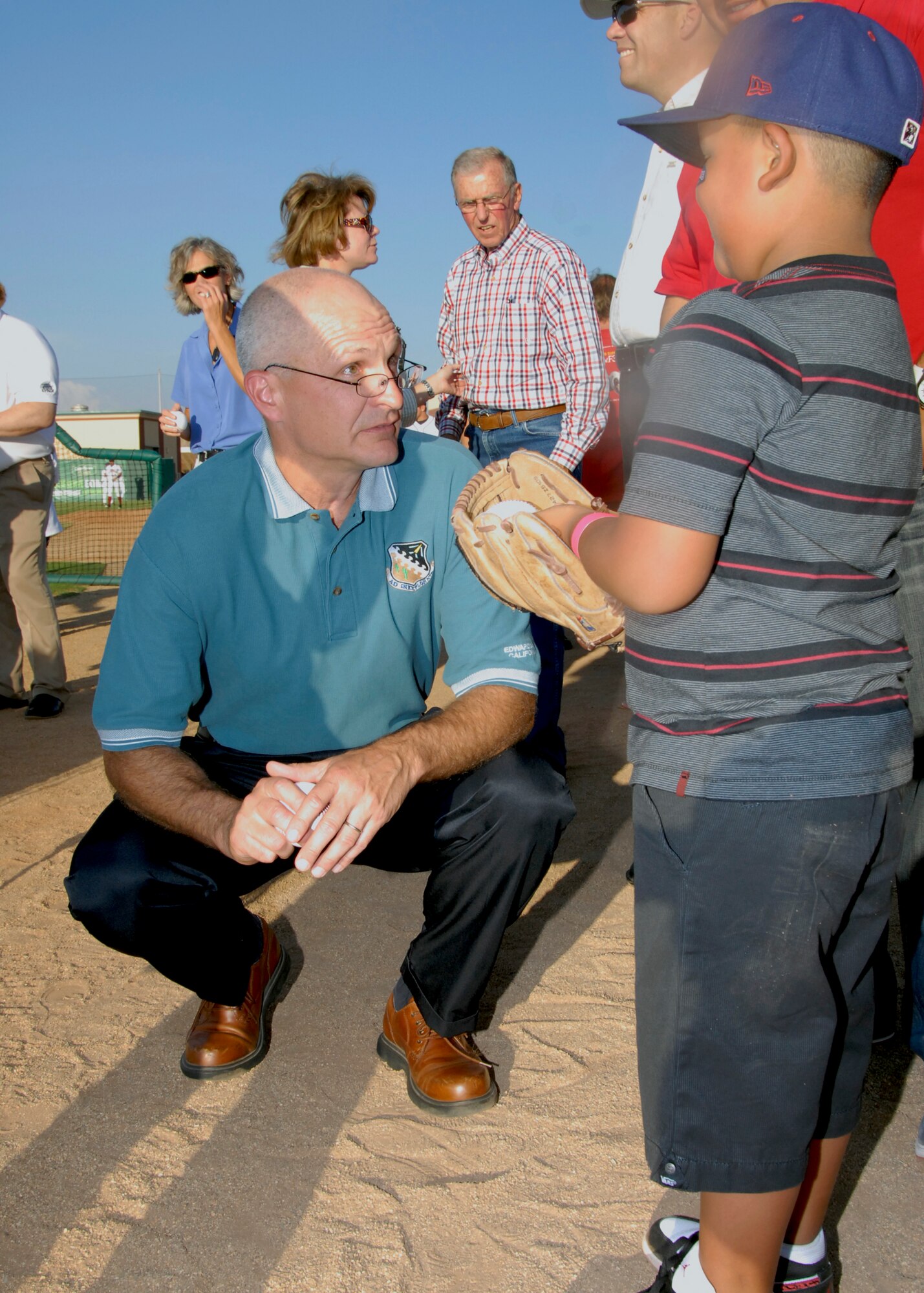 Brig. Gen. Arnold W. Bunch, Air Force Test center commander, takes a few minutes to talk with a young boy before throwing a ceremonial first pitch at JetHawk stadium in honor of Aerospace Appreciation Night. (Air Force Photo by Laura Mowry)