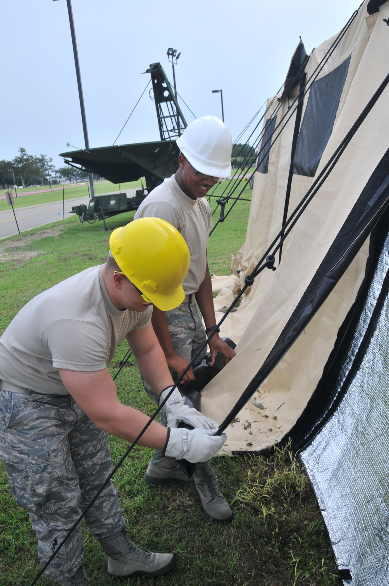 Airman 1st Class Craig Bodden (left) and Airman Shermonte Gilbert, 336th Training Squadron students, fold down the side flaps of a new Air Expeditionary Force tent after securing it to the ground July 31, 2012, at the Triangle training area, Keesler Air Force Base, Miss. The new AEF tents that students are training with are the same model currently being used in deployments and provides better ventilation for the Airmen and equipment.  (U.S. Air Force photo by Senior Airman Eric Summers, Jr.)