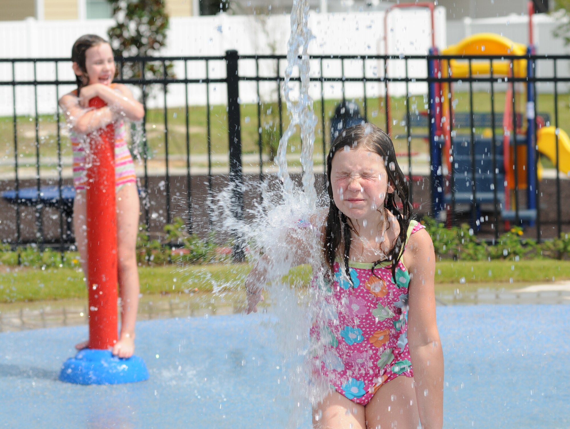 Katie Lewis, 7, and her sister, Emma, 8, play together on the splash pad at the Keesler Community Center in the Bay Ridge housing area August 7, 2012, at Keesler Air Force Base, Miss. Katie and Emma are the daughters of Kimberly and Brad Lewis, who are here visiting family at Keesler.  The center celebrated its opening with a ribbon-cutting ceremony and a tour of the facility, which also features an event room, business center, fitness room with a children’s play area, and an outdoor swimming pool.  (U.S. Air Force photo by Kemberly Groue)