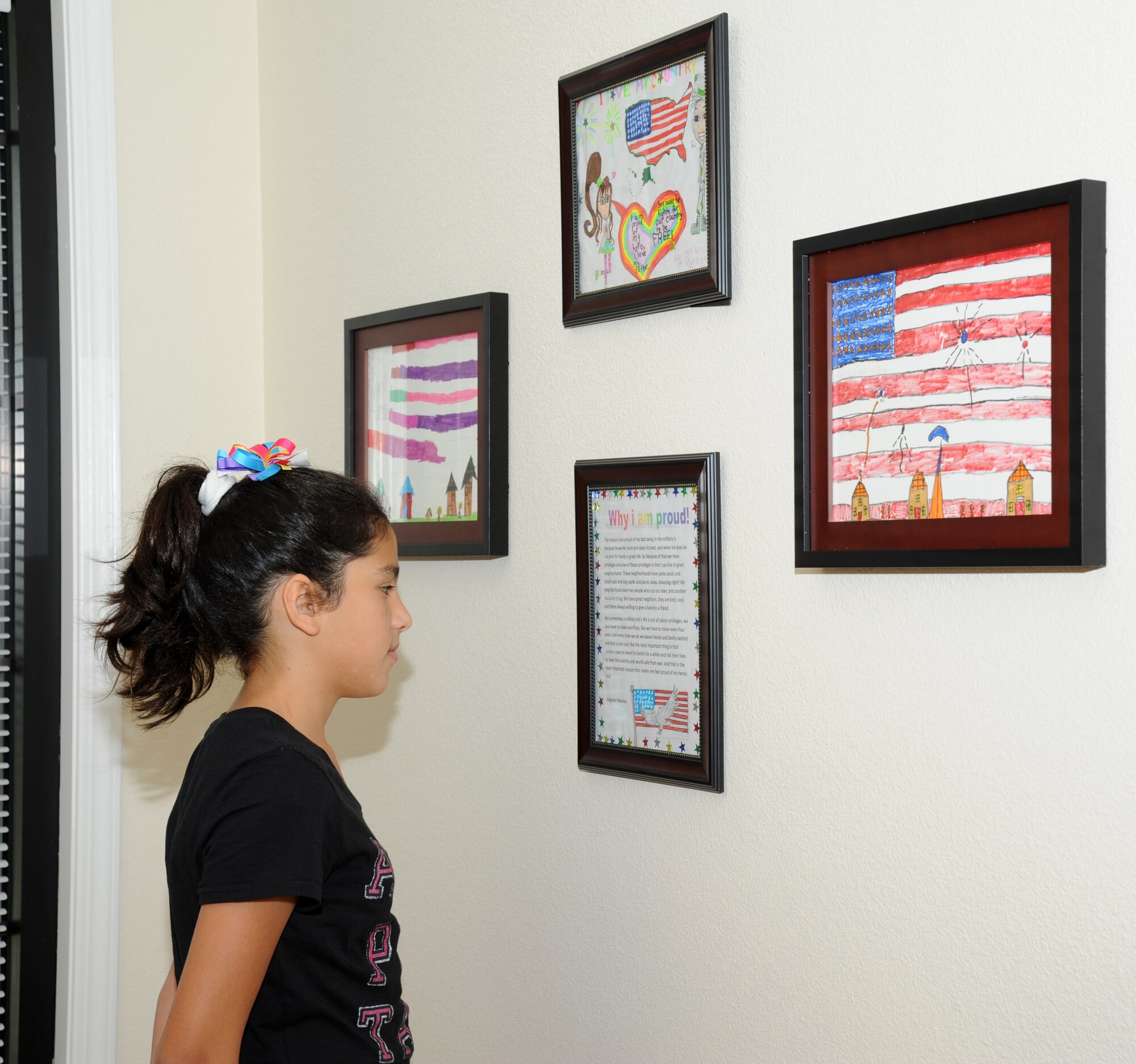 Eleven-year-old Angelee Morales, daughter of Yoseline and Staff Sgt. Pedro Morales, 338th Training Squadron, admires her winning essay on display at the Keesler Community Center  in the Bay Ridge housing area August 7, 2012, at Keesler Air Force Base, Miss.  The center celebrated its opening with a ribbon-cutting ceremony and a tour of the facility, which features an event room, business center, fitness room with a children’s play area, an outdoor swimming pool and a splash pad.  Angelee’s essay along with three other children’s winning art work hang on display.  (U.S. Air Force photo by Kemberly Groue)