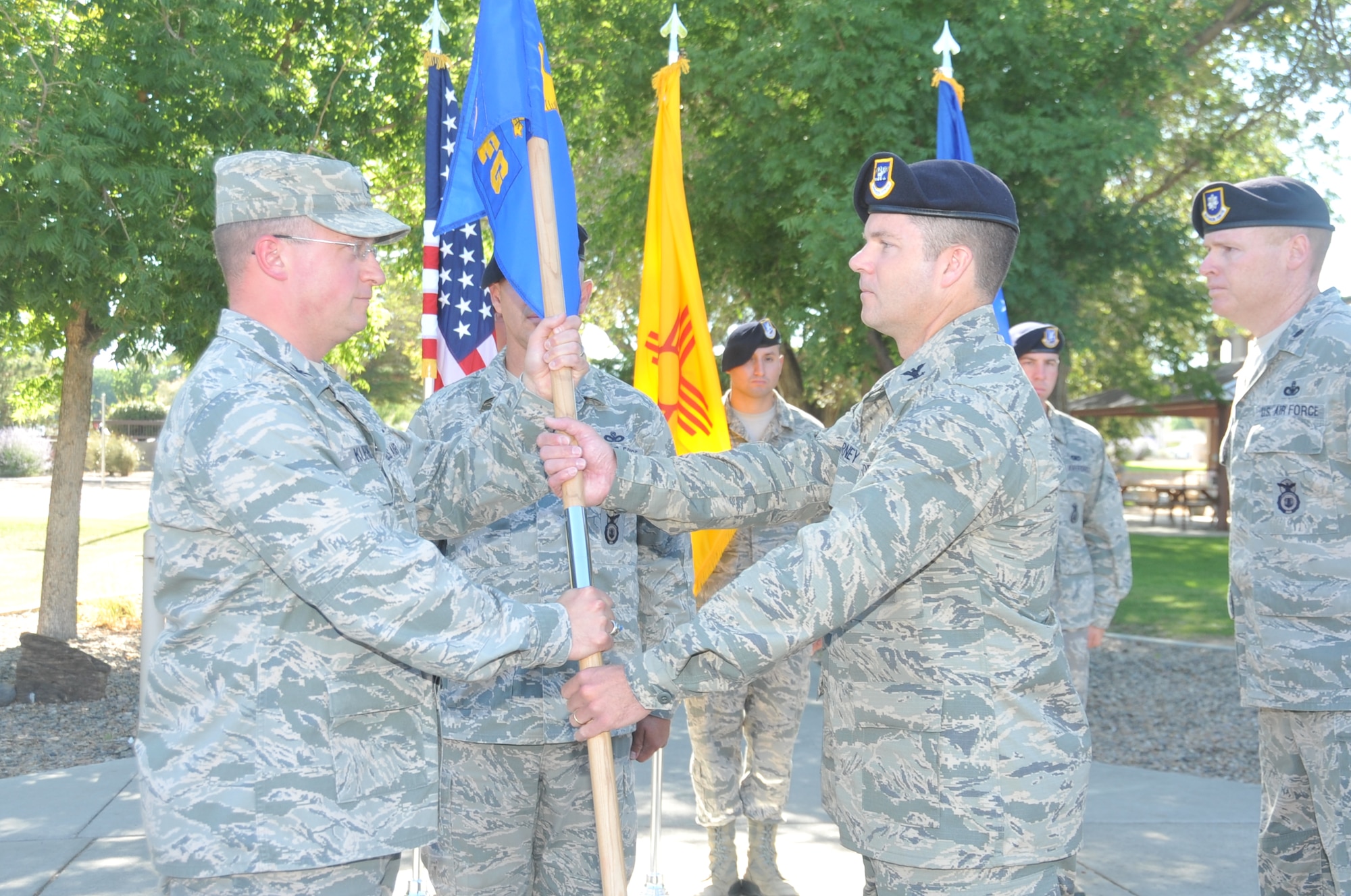 KIRTLAND AFB, N.M. -- Col. John Kubinec, left, 377th Air Base Wing commander, passes the 377th Security Forces Group guidon to Col. Paul Barney in a change of command ceremony July 20 at Kirtland Air Force Base.  (Photo by Todd Berenger)