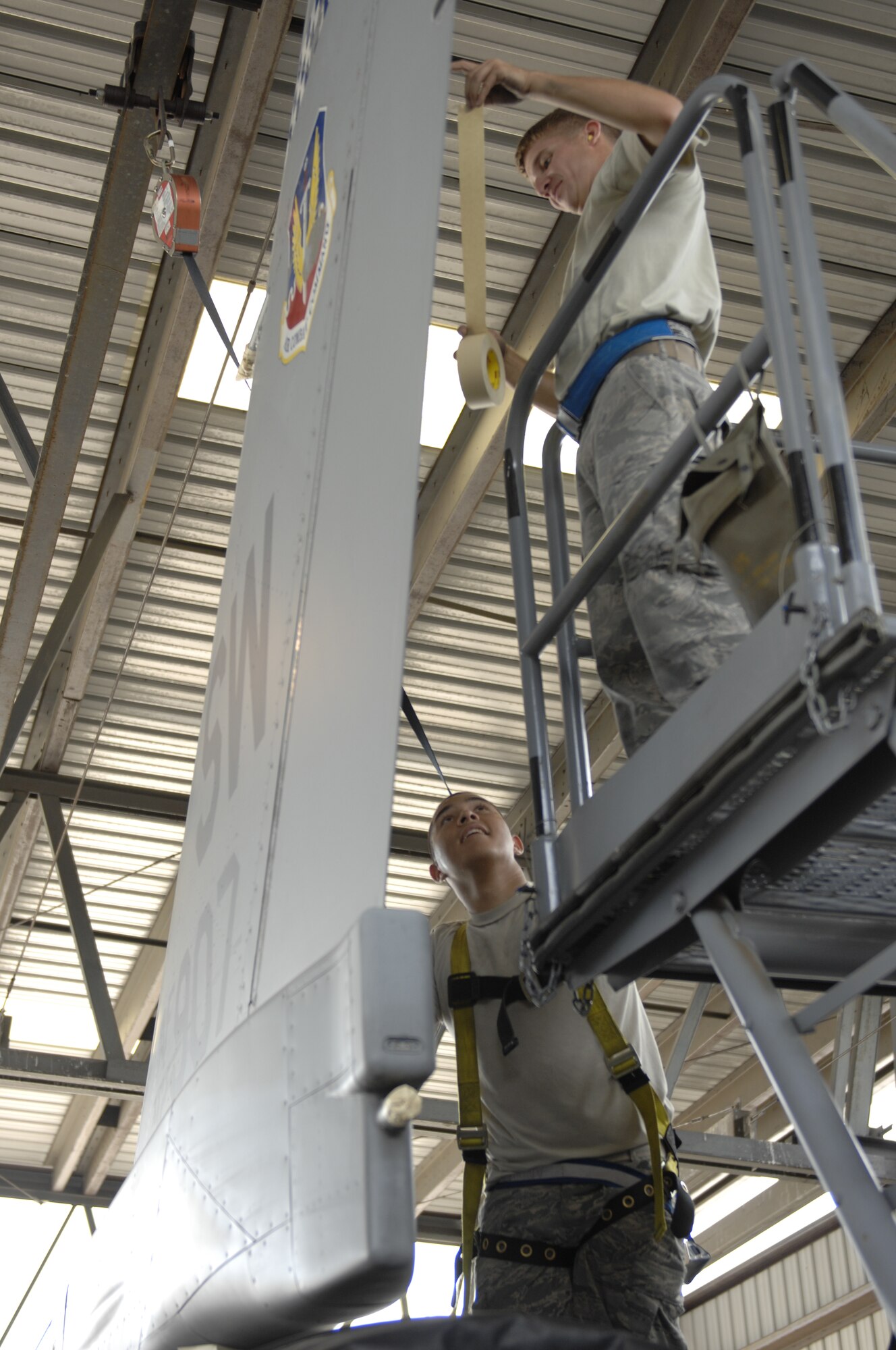 Staff Sgt. Kyle Padgett, 20th Aircraft Maintenance Squadron, Gamblers Aircraft Maintenance Unit, a dedicated crew chief and a native of Aiken, S.C., and Airman 1st Class Matthew Andrade, Gamblers AMXU crew chief and a native of Vacaville, Calif., apply tape to the tail of an F-16 Fighting Falcon at Shaw Air Force Base, S.C., July 31, 2012. The purpose of the tape is to protect sensitive electrical equipment while the plane is washed of dirt, grime and other debris. Planes are washed every 180 days to prevent corrosion. (U.S. Air Force photo by Airman 1st Class Krystal M. Jeffers/Released)