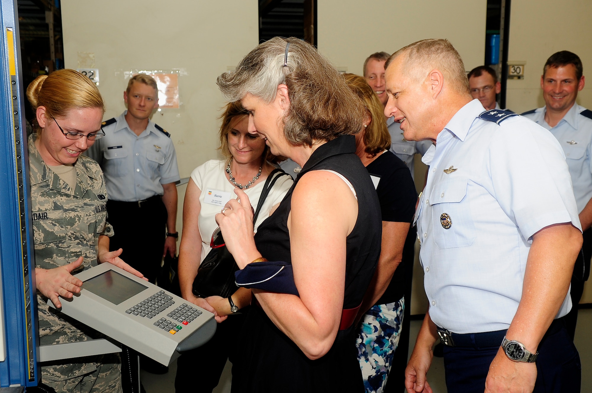 U.S. Air Force Airman 1st Class Jennifer Adair, aircraft parts store apprentice, explains how the vertical lift machine works to Maj. Gen. Lawrence Wells, 9th Air Force commander, and his wife Kathy Wells, in the 20th Logistics Readiness Squadron F-16 Fighting Falcon parts store at Shaw Air Force Base, S.C., Aug. 6, 2012. The vertical lift machine is used to hold tools and other items to maximize storage space in the parts store. Wells visited different squadrons on base to speak with Airmen and understand their mission and daily duties. (U.S. Air Force photo by Airman 1st Class Hunter Brady/Released)