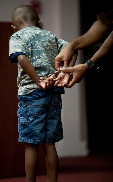 A child is handcuffed during an Air Force Office of Special Investigations demonstration for Operation Deployment Aug. 3, 2012, at Incirlik Air Base, Turkey. The event gave children and spouses of service members the opportunity to learn about the deployment process. Almost 200 people participated in the event. (U.S. Air Force photo by Senior Airman Clayton Lenhardt/Released)