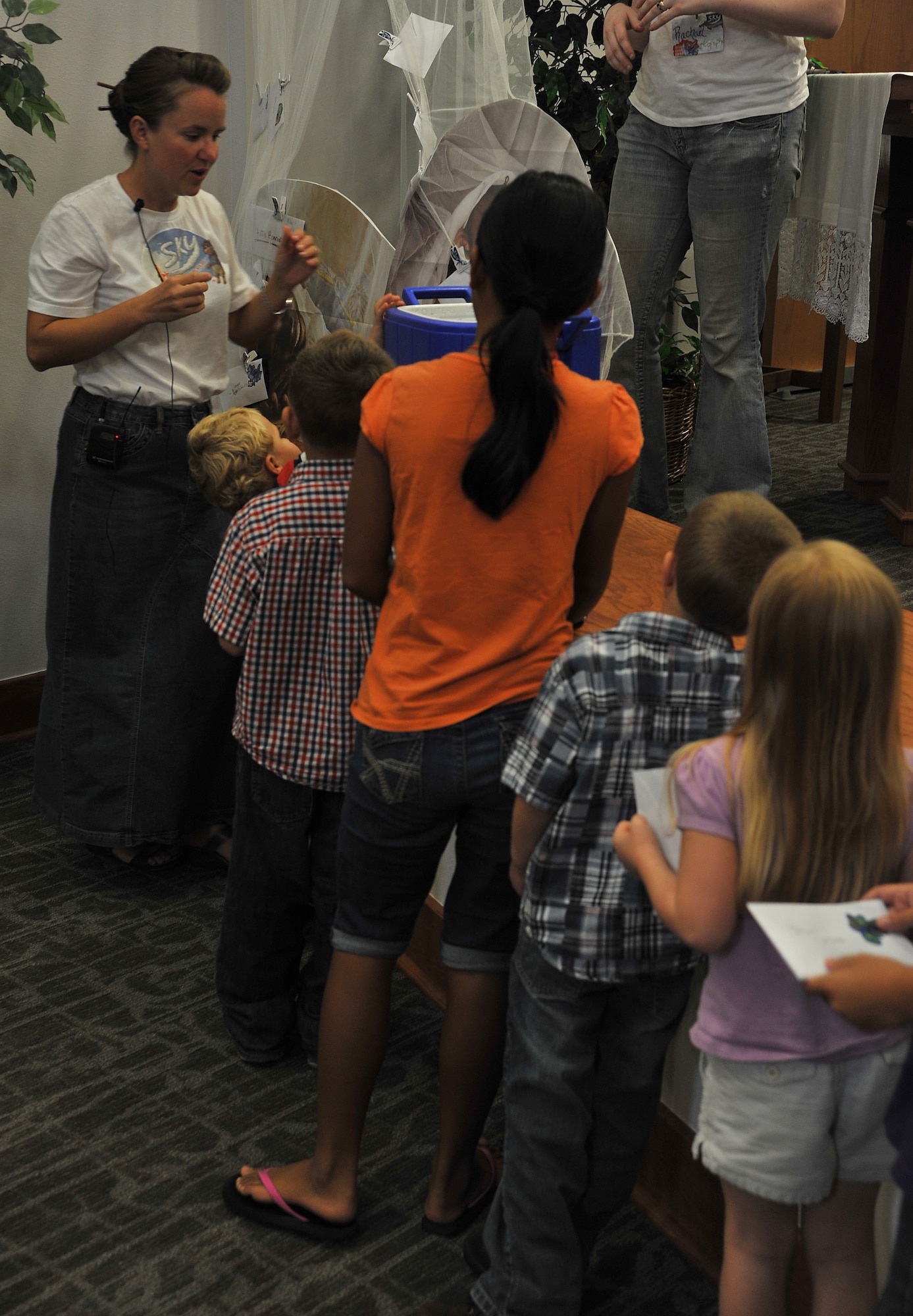 GOODFELLOW AIR FORCE BASE, Texas-- Bonnie Averett, 17th Training Wing Chapel volunteer, helps the children of vacation bible school place donations in the Taylor Chapel Aug. 3. The children raised money for mosquito nets to protect less fortunate kids from malaria. (U.S. Air Force photo/Airman 1st Class Michael Smith) 