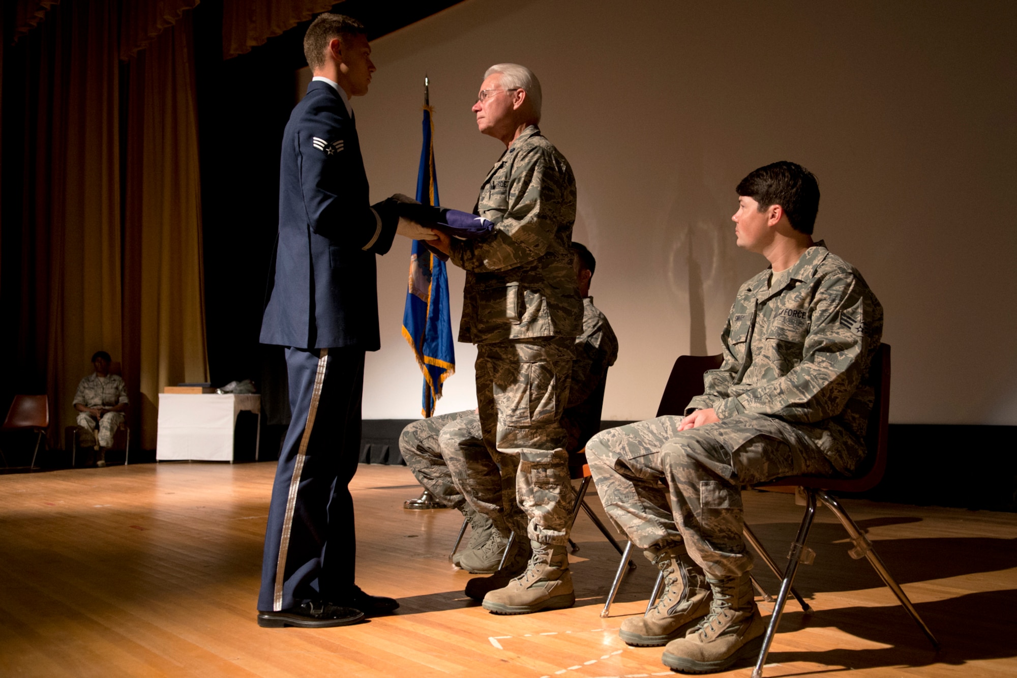 A member of the Barksdale Air Force Base Honor Guard, presents an American Flag to U.S. Air Force Lt. Col. Allen Smith during his retirement ceremony on Barksdale Air Force Base, La., Aug 8, 2012. Smith is retiring after serving 35 years in the military and asked his two sons, Staff Sgt. Patrick Smith and Senior Airman Eric Smith, to join him onstage during the ceremony. (U.S. Air Force photo by Master Sgt. Greg Steele/Released)