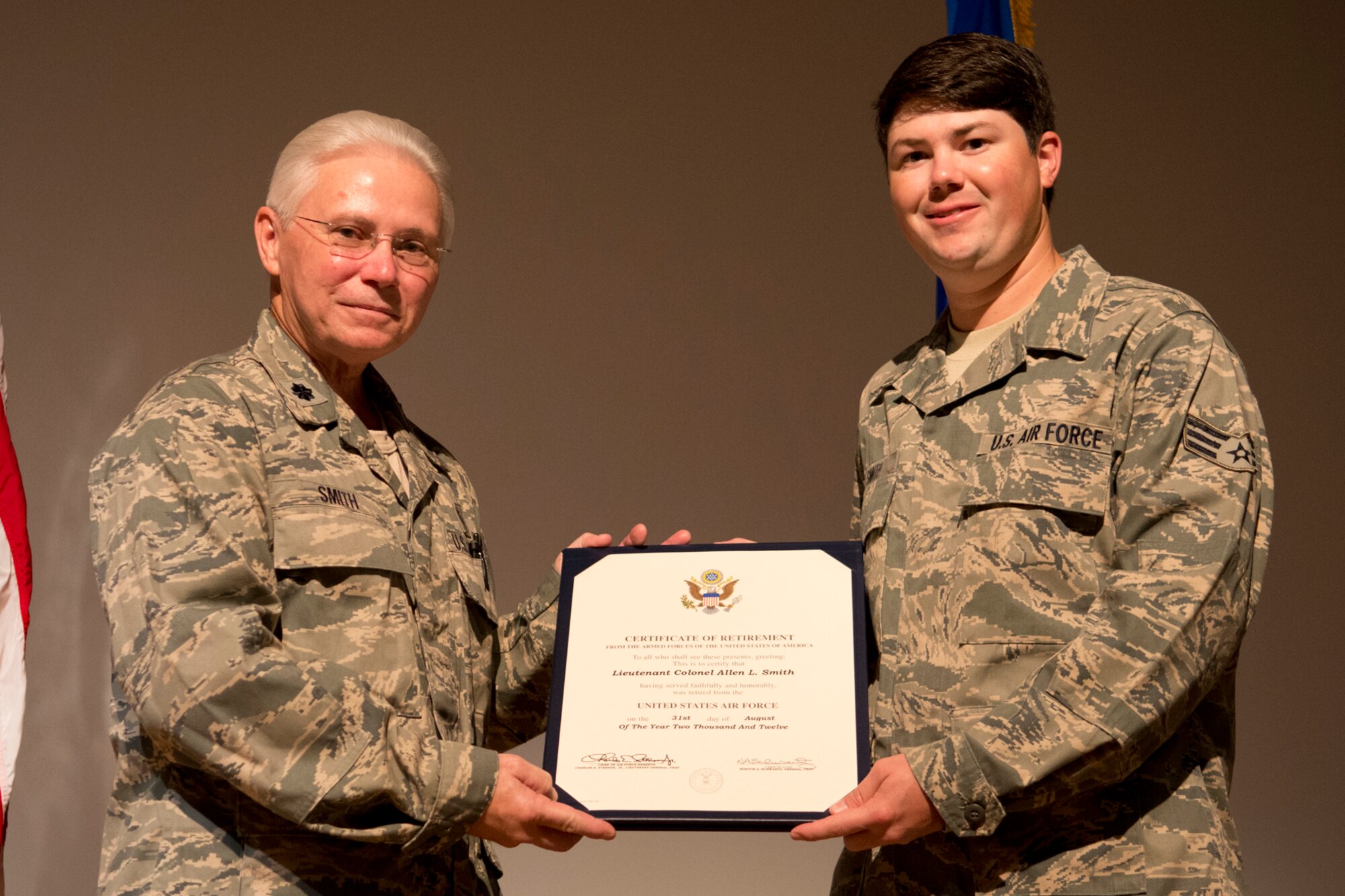 U.S. Air Force Senior Airman Eric Smith presents his dad, Lt. Col. Allen Smith, with a Certificate of Retirement during a ceremony on Barksdale Air Force Base, La., Aug. 5, 2012. Lt. Col. Smith is assigned to the 307th Medical Squadron and is retiring after serving 35 years in the military. (U.S. Air Force photo by Master Sgt. Greg Steele/Released)