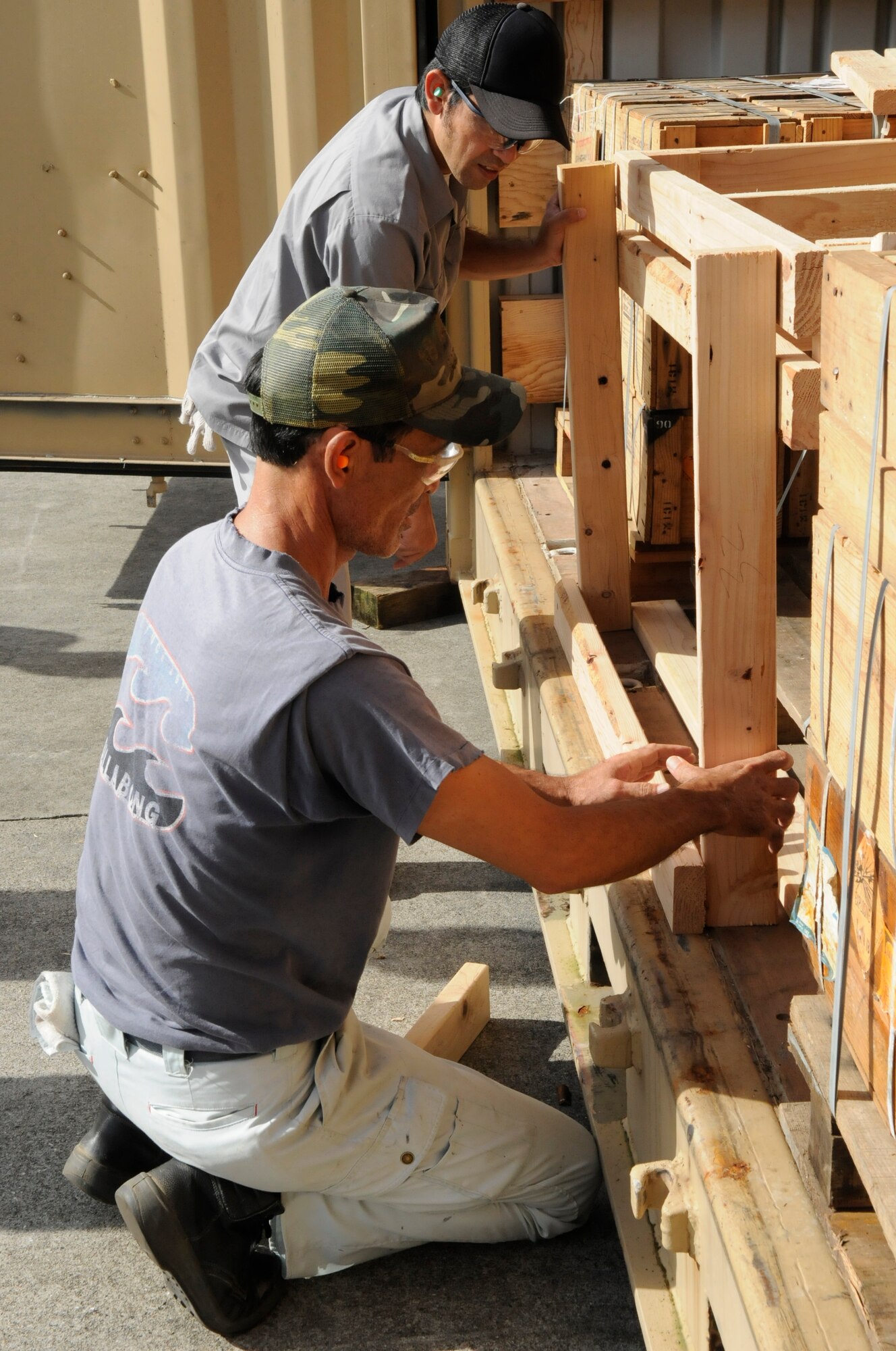 Members of the 18th Munitions Squadron align wooden beams that will frame pallets for munitions being shipped in cargo containers from Kadena Air Base, Japan, July 31, 2012. The frames are used to ensure the pallets don't shift during transportation throughout the Pacific Air Forces. (U.S. Air Force photo/Airman Tara A. Williamson)
