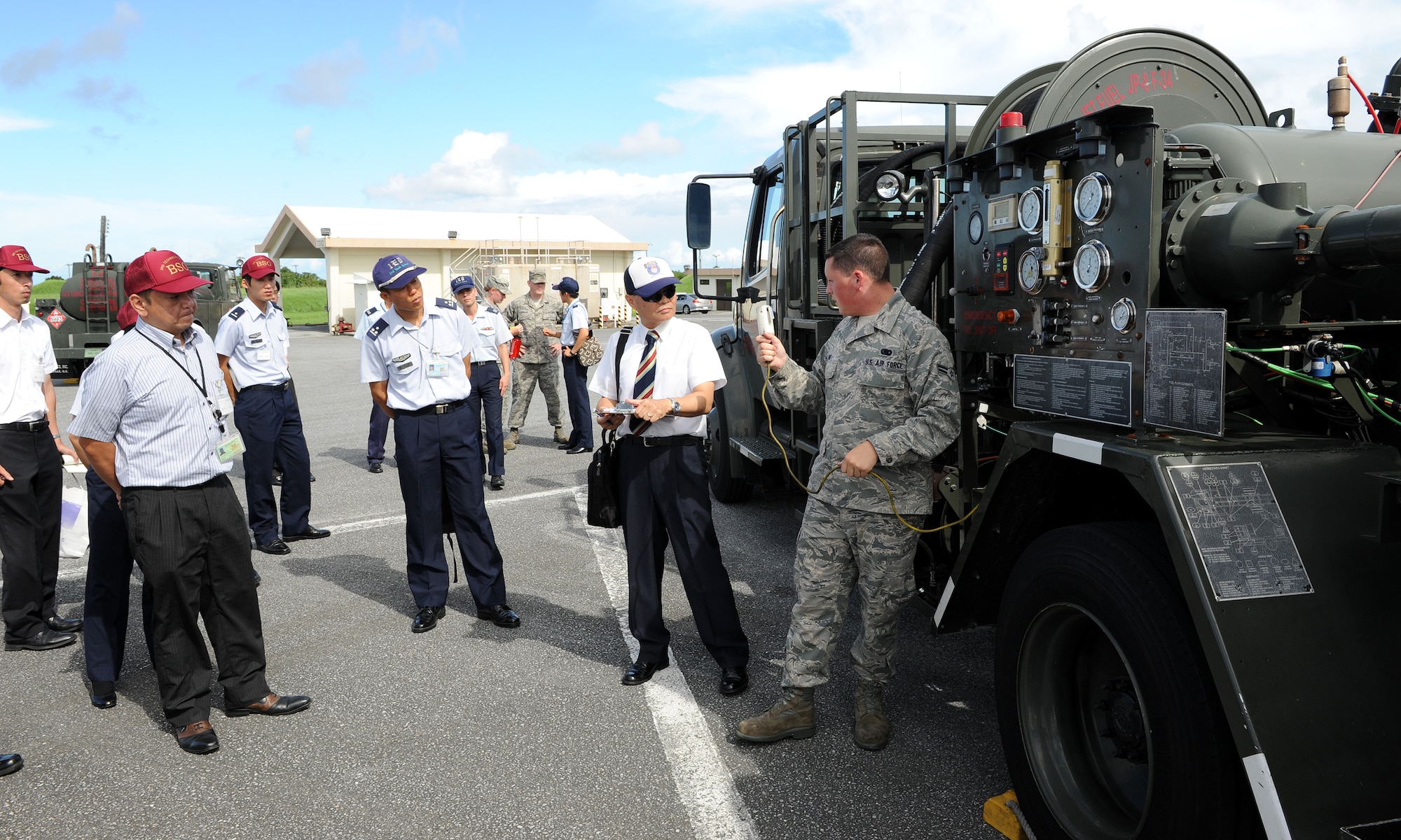U.S. Air Force Airman 1st Class James Hunt, 18th Logistics Readiness Squadron, explains the R-12 gas truck to Japan Air Self-Defense Force members visiting LRS facilities at Kadena Air Base, Japan, July 25, 2012. Hunt showed the JASDF members how to stop and check the safety of the R-12 gas trucks at the fuels yard. (U.S. Air Force photo/Junko Kinjo)