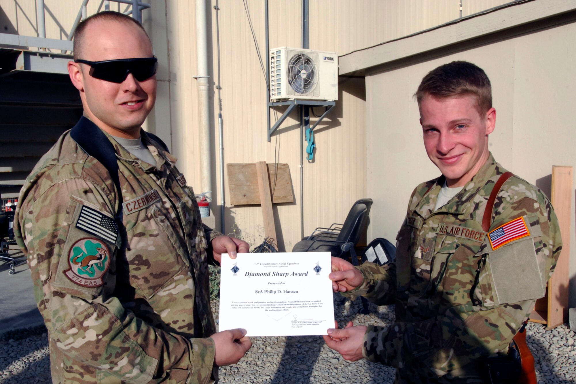 Senior Airman Philip Hansen (right), 774th Expeditionary Airlift Squadron Joint Airdrop Inspector, receives the “Diamond Sharp” award from MSgt Scott Czerwinski, 774 EAS First Sergeant, at Bagram Airfield, Afghanistan, Aug. 7, 2012. The “Diamond Sharp” award is presented by the 1st Sergeants Group to an Airman in a unit who stands out amongst their peers based on professionalism, performance of duty, and wear of uniform. With the Diamond Sharp Award having just been revamped, Hansen was the first Airman to receive the award since it started back up. (U.S. Air Force photo/SSgt Jeff Nevison)