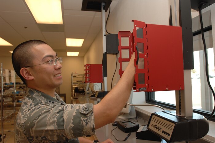 U.S. Air Force Capt. Sang Ngo, 99th Medical Support Squadron, outpatient pharmacy chief, loads the new Trans Trax system with a prescription on Aug.7, 2012 at the satellite pharmacy at Nellis Air Force Base, Nev. The satellite pharmacy opened the drive-thru Aug. 6  after a $100,000 upgrade. (U.S. Air Force photo by Master Sgt. David Miller)