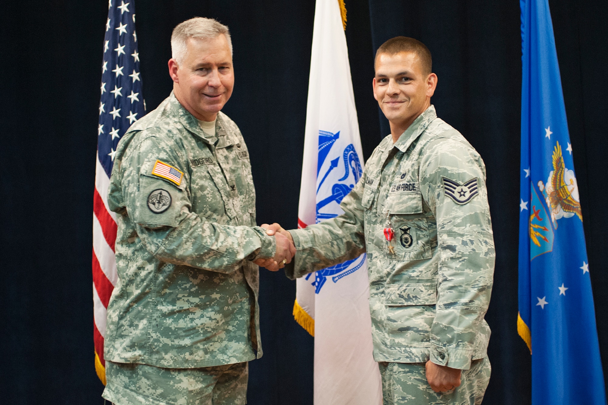 U.S. Army Col. Robert Bridgford, 502nd Air Base Wing vice commander, congratulates Staff Sgt. Christopher Keilman, 902nd Security Forces Squadron military working dog handler, after presenting him with the Bronze Star Medal July 31 at the Joint Base San Antonio-Randolph Kendrick Club. (U.S. Air Force photo by Benjamin Faske)
