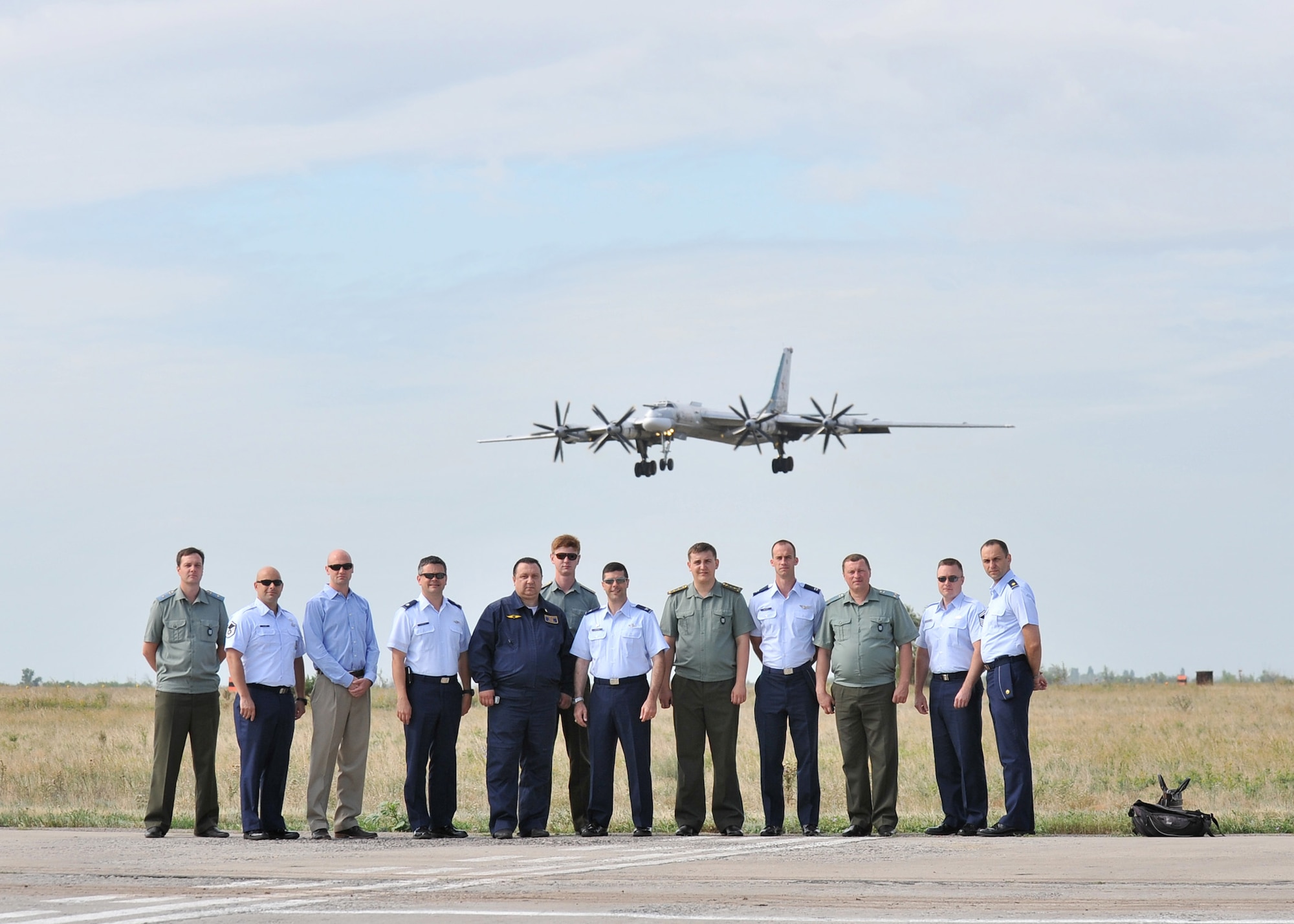 Barksdale Air Force Base members and Russian Federation air force personnel pose for a group photo as a Tu-95 “Bear” bomber prepares to land at Engels Air Base, Russia, July 25. Col. Andrew Gebara, 2nd Bomb Wing commander, and a team of experts visited the Russian base to determine the suitability of the airfield for B-52H Stratofortress operations. (Courtesy photo)