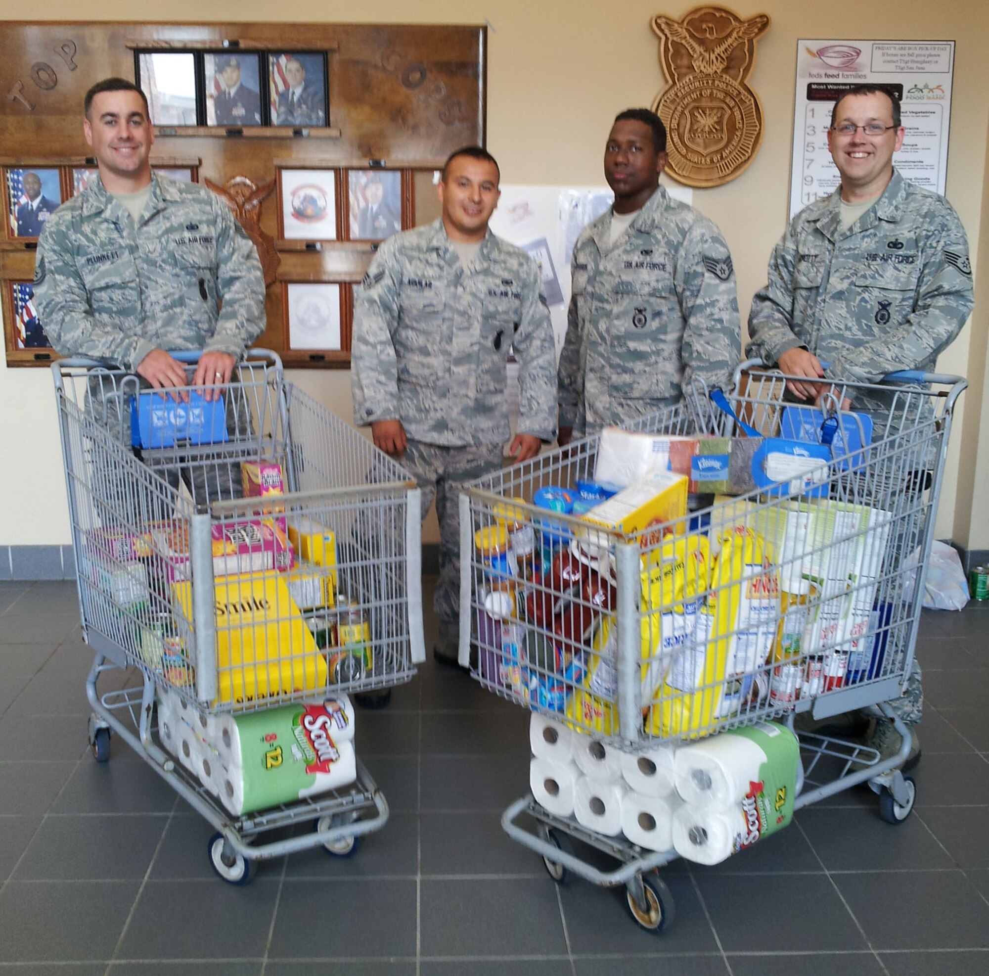 HANSCOM AIR FORCE BASE, Mass. – Members of the 66th Security Forces Military Working Dog Team, (left to right) Tech. Sgt. Matt Plunkett, Senior Airman Francisco Aguilar, Staff Sgt. Victor Portes-Garcia, and Staff Sgt. Richard Crotty, cart items into Building 1725 to donate to the Feds Feed Families food drive. The drive runs through Aug. 31. (Courtesy photo)