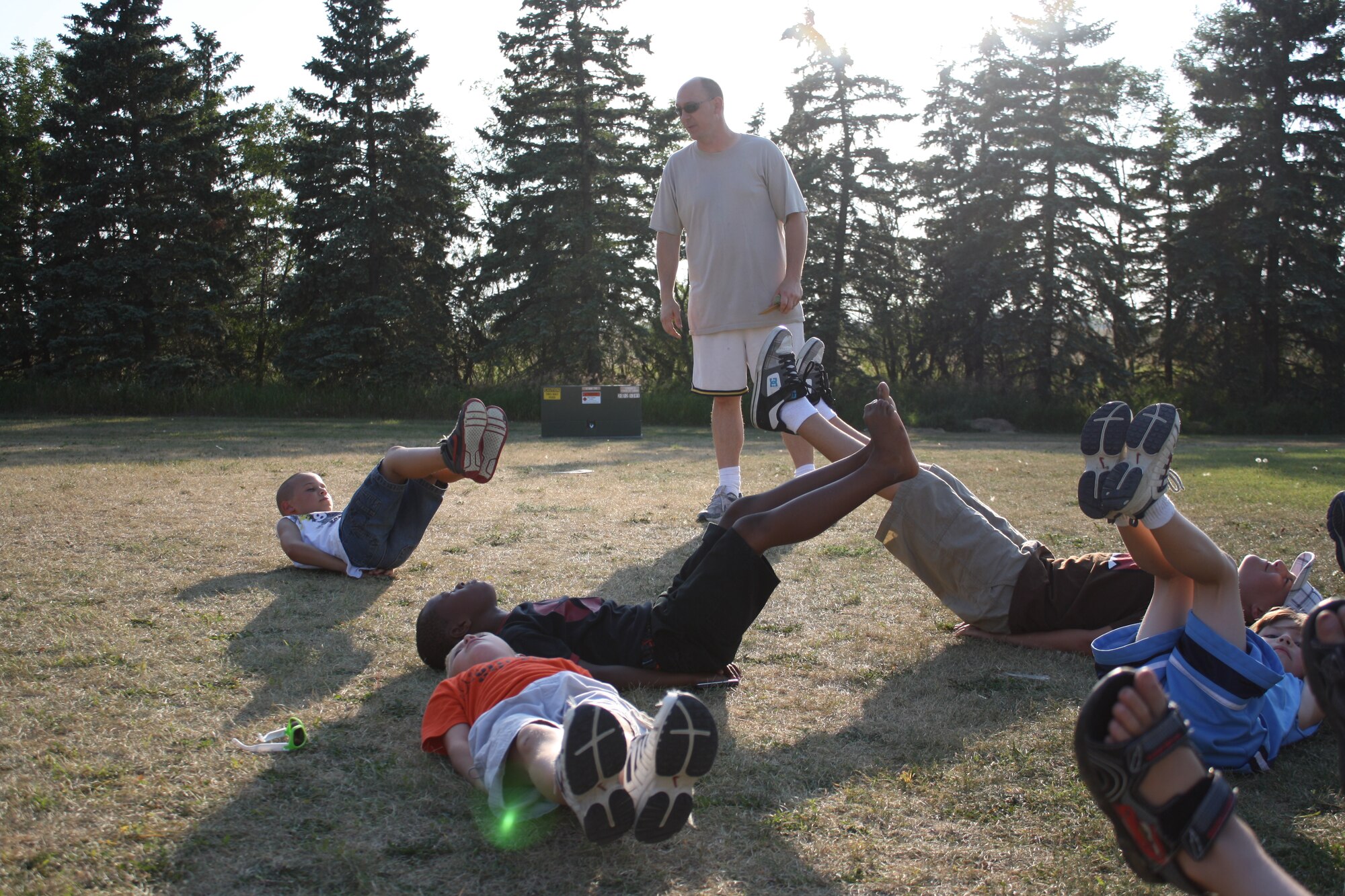 MINOT AIR FORCE BASE, N.D. -- Tech. Sgt. Jeremy Greene, 5th Aircraft Maintenance Squadron, watches his "boot camp" kids as they perform flutter kicks during an afternoon of fun and exercise here recently. Sergeant Greene created the exercise group as a way to help the local neighborhood children stay fit and have fun. (U.S. Air Force photo/Kiley Swopes)