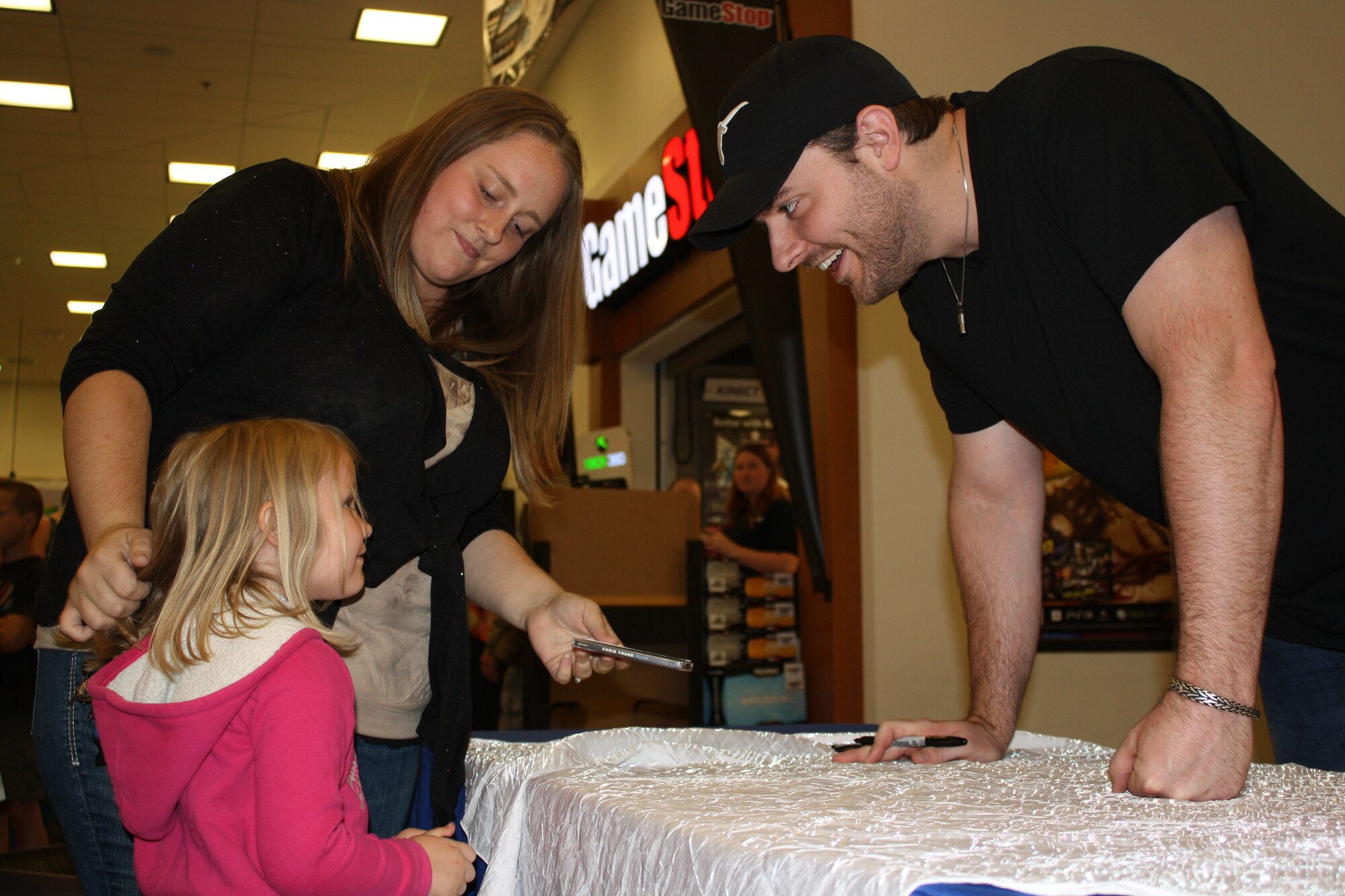 MINOT AIR FORCE BASE, N.D. -- Current American Country Award winner for Breakthrough Artist of the Year and Single of the Year, Chris Young, talks to a young fan during an autograph signing event held at the Minot Air Force Base Exchange here, July 27. Young took time out of his tour schedule to sign autographs for Team Minot Airmen and their families, as well as meet Scott Lilley, a wounded warrior and former 5th Security Forces Squadron Airman. (U.S. Air Force photo/Kiley Swopes)

