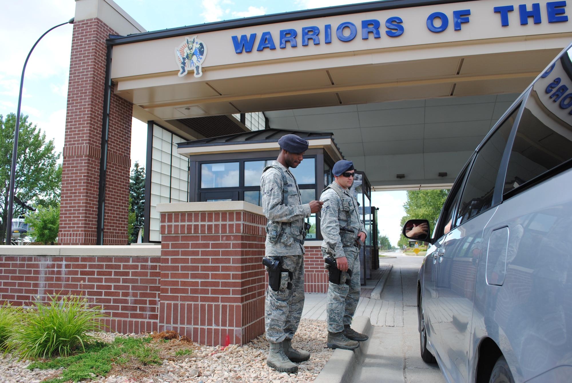 (From left) Airmen 1st Class Erik Carter and Jason Harvey verify the identification of a motorist arriving at the main gate of Grand Forks Air Force Base, N.D. , on Aug. 2, 2012. The two installation entry controllers from the 319th Security Forces Squadron were the first Airmen to monitor traffic flow in and out of base’s main gate after it reopened that day.  (U.S. Air Force photo/Senior Airman Luis Loza Gutierrez)