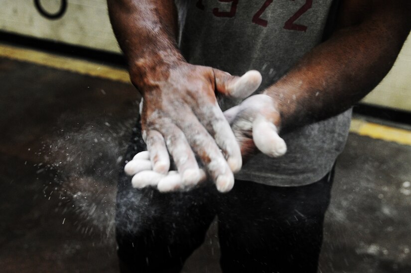 Tech Sgt. Denoris Mickle, 1st Combat Camera Squadron photographer, brushes off extra chalk from his hands before demonstrating the correct dead lift technique during a weightlifting test Aug. 3, 2012, at the fitness center at Joint Base Charleston - Air Base, S.C.  The weightlifting test included bench press, squats, dead lifts and pull-ups. The total amount each Airman lifted was divided by their body weight to give a pound-for-pound strength score in both the male and female categories.  The voluntary program was the first weight lifting test held by the 1st CTCS.  It was started by the unit’s fitness monitors to motivate Airmen to diversify their workouts and show them the importance of incorporating strength training.  (U.S. Air Force photo/ Staff Sgt. Nicole Mickle)