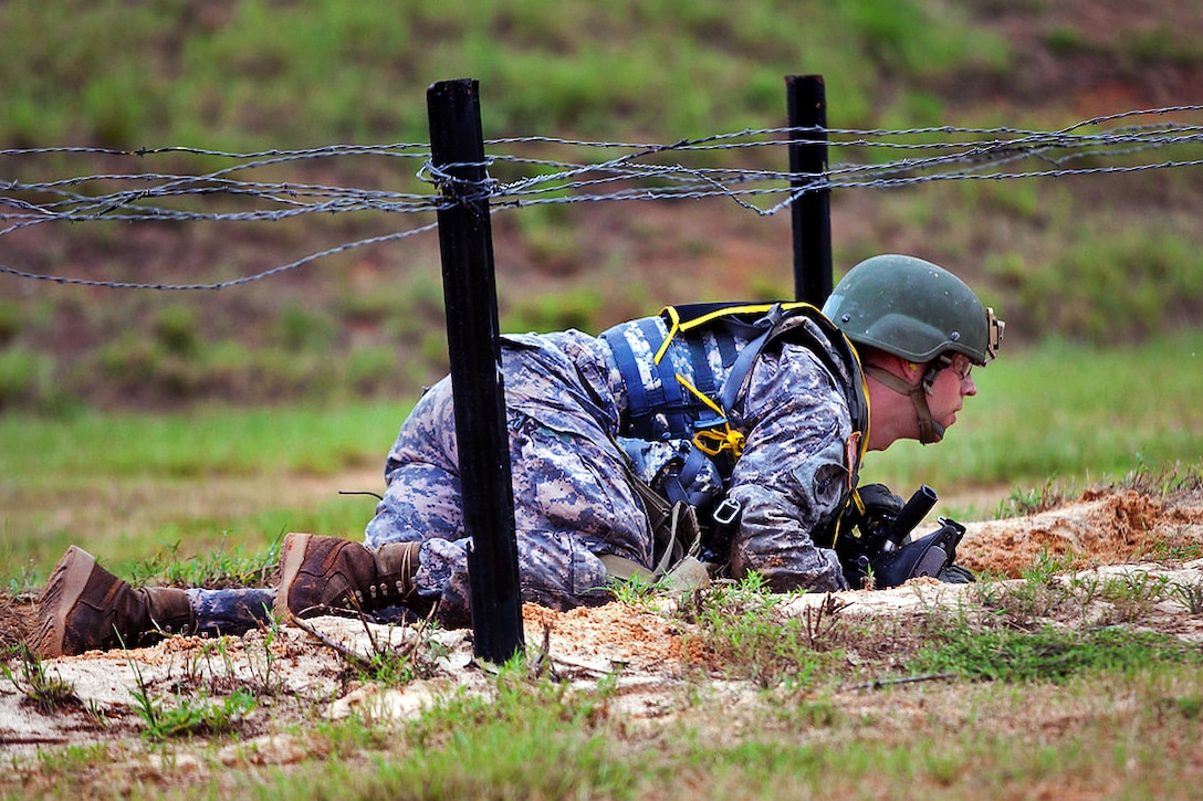 A soldier low crawls under barbed wire with his M4 assault rifle during the Best Warrior Competition on Fort Benning, Ga., July 31, 2012.