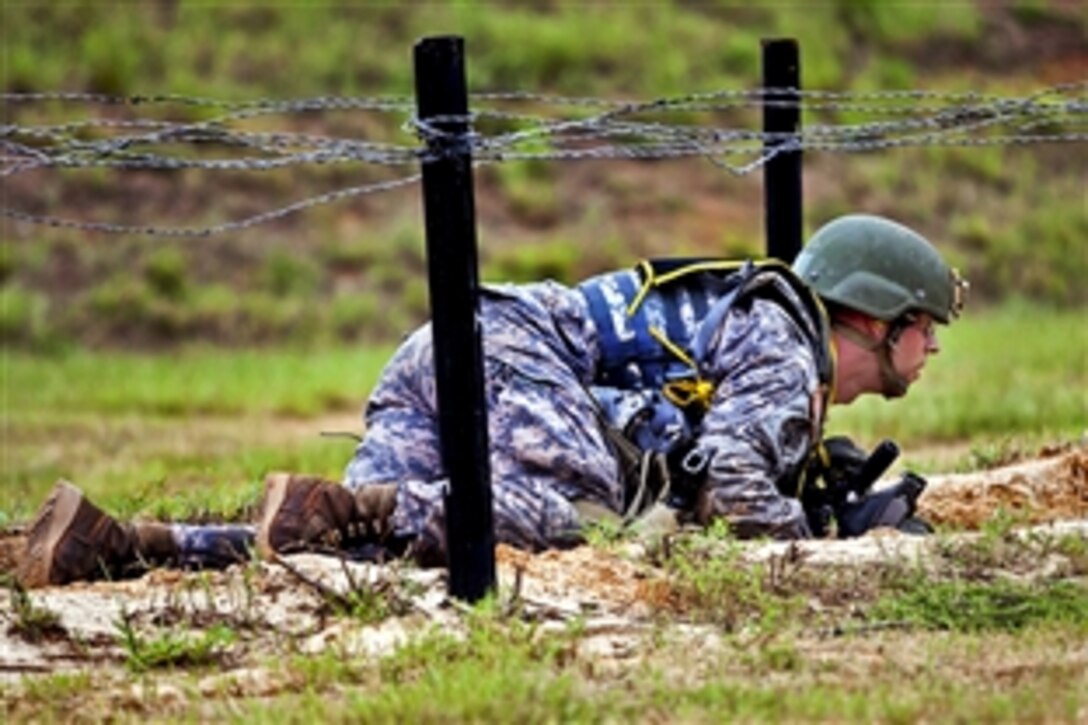 A soldier low crawls under barbed wire with his M4 assault rifle during the Best Warrior Competition on Fort Benning, Ga., July 31, 2012.