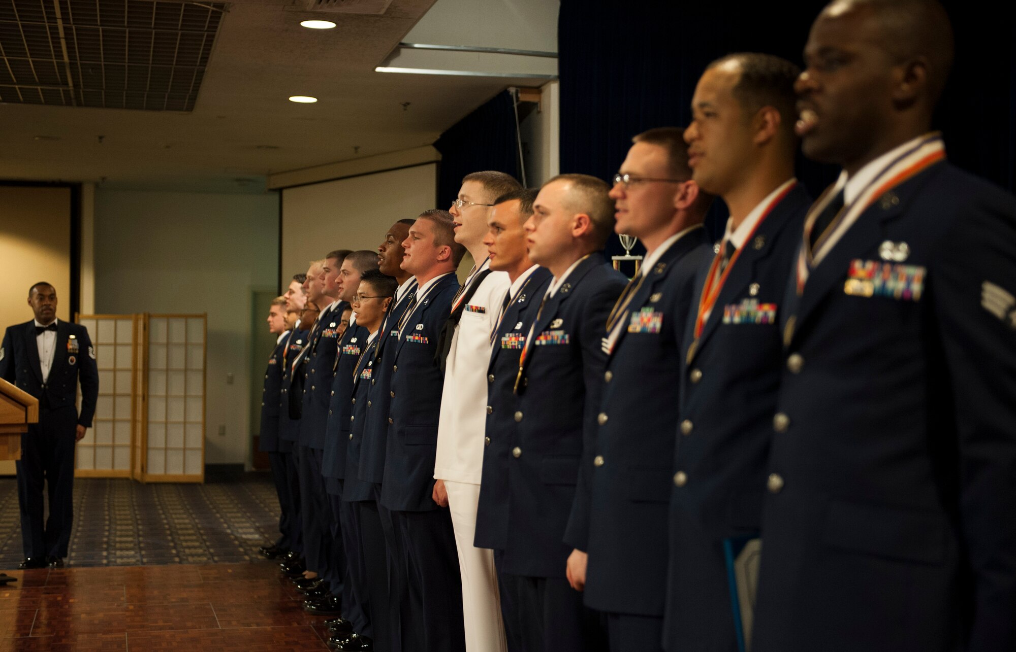 YOKOTA AIR BASE, Japan -- Airman Leadership School Class 12-F sing the Air Force song at the end of their graduation at the Yokota Enlisted Club, Yokota Air Base, Japan, Aug. 9, 2012. ALS graduated 17 airmen and one sailor, Petty Officer 3rd Class William Bossom, Department of Defense Special Representative, Japan. Bossom learned the Airmen's Creed while also teaching the other classmates the Navy's creed. (U.S. Air Force photo by Senior Airman Andrea Salazar)