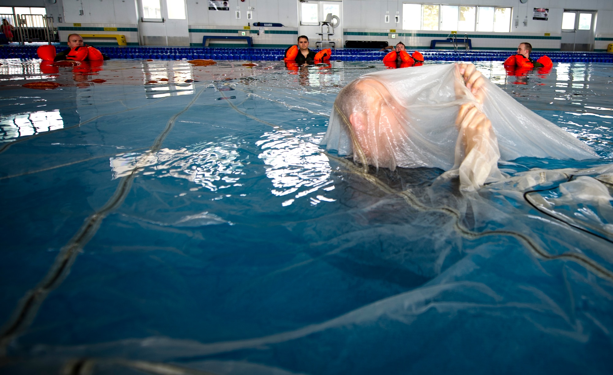 YOKOTA AIR BASE, Japan -- Tech. Sgt. Benjamin Rosciglione, 374th Operation Support Squadron survival, evasion, resistance and escape instructor, demonstrates how to navigate under a parachute canopy during SERE training, July 24, 2012, at Yokota Air Base, Japan. Students learn how to stay calm and move under the canopy after landing in the water. (U.S. Air Force photo by Staff Sgt Stacy Moless)