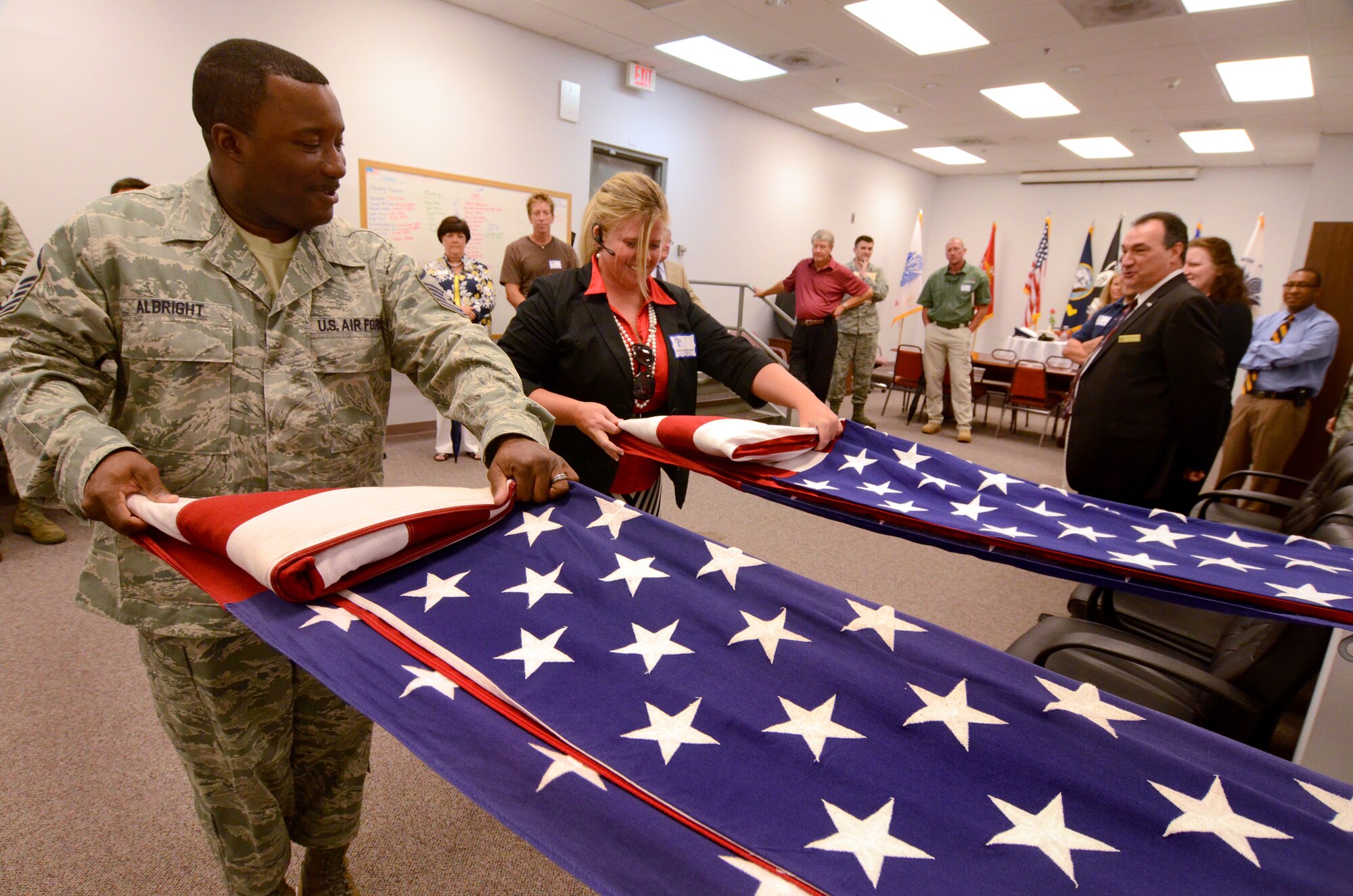 Master Sgt. Aaron Albright, noncommissioned officer in charge of the 94th Airlift Wing honor guard, leads Ashley Vandiver through a flag folding exercise at Dobbins Air Reserve Base, Aug. 9. Members of the Hercules Council, comprised of area civic leaders, had lunch on base and visited the 94th Airlift Wing honor guard to get a better understanding of what they do for the local community and region. (U.S. Air Force photo/Brad Fallin)