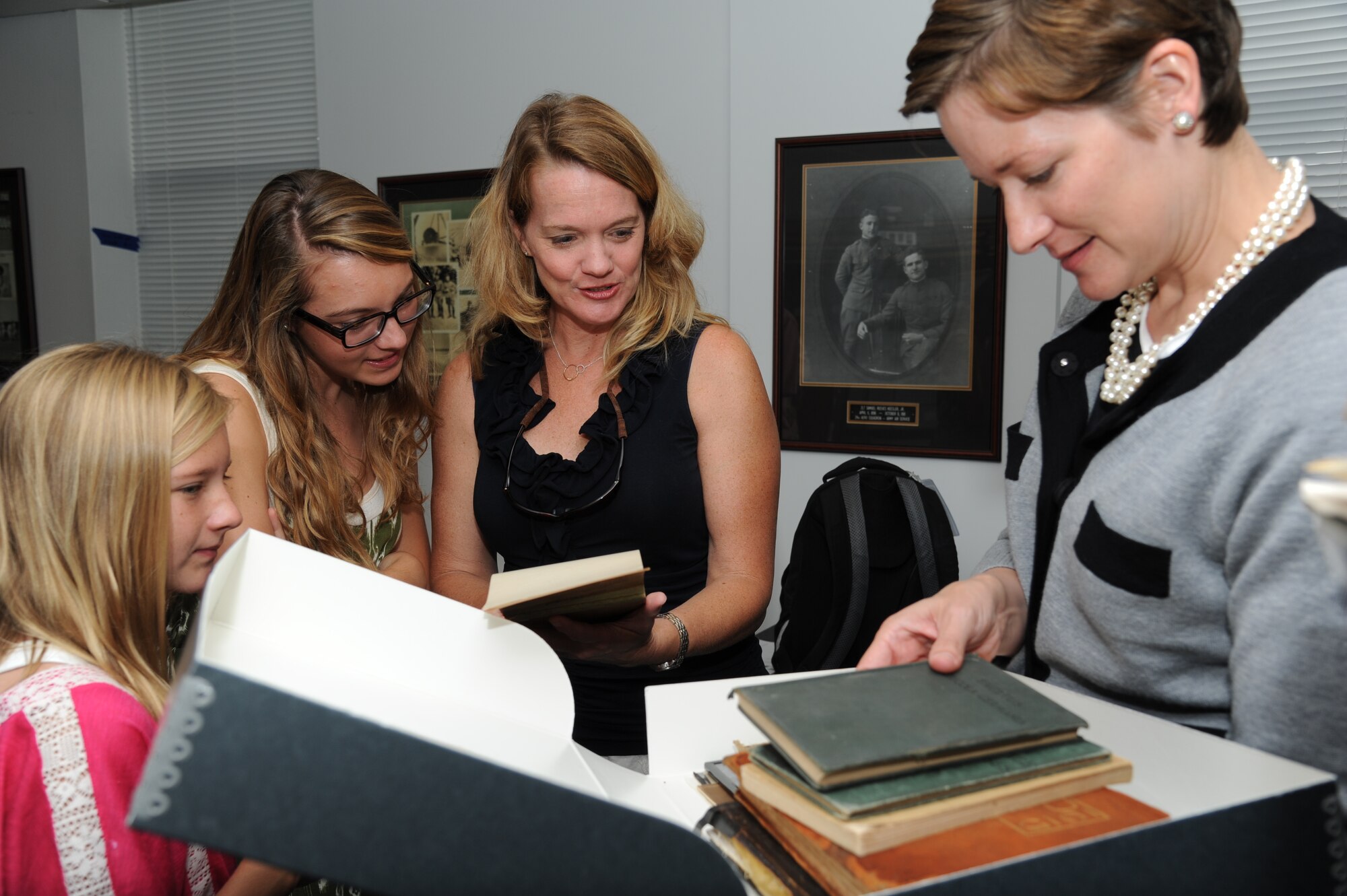 Tate Mueller, 11, along with her sister, Lee, 16, her mother, Sally, and Susan Dawson, 81st Training Wing base historian, view old school books and yearbooks belonging to 2nd Lt. Samuel Keesler August 9, 2012, at the 81st Training Wing Headquarters, Keesler Air Force Base, Miss.  Sally is the great-niece of Keesler.  (U.S. Air Force photo by Kemberly Groue)