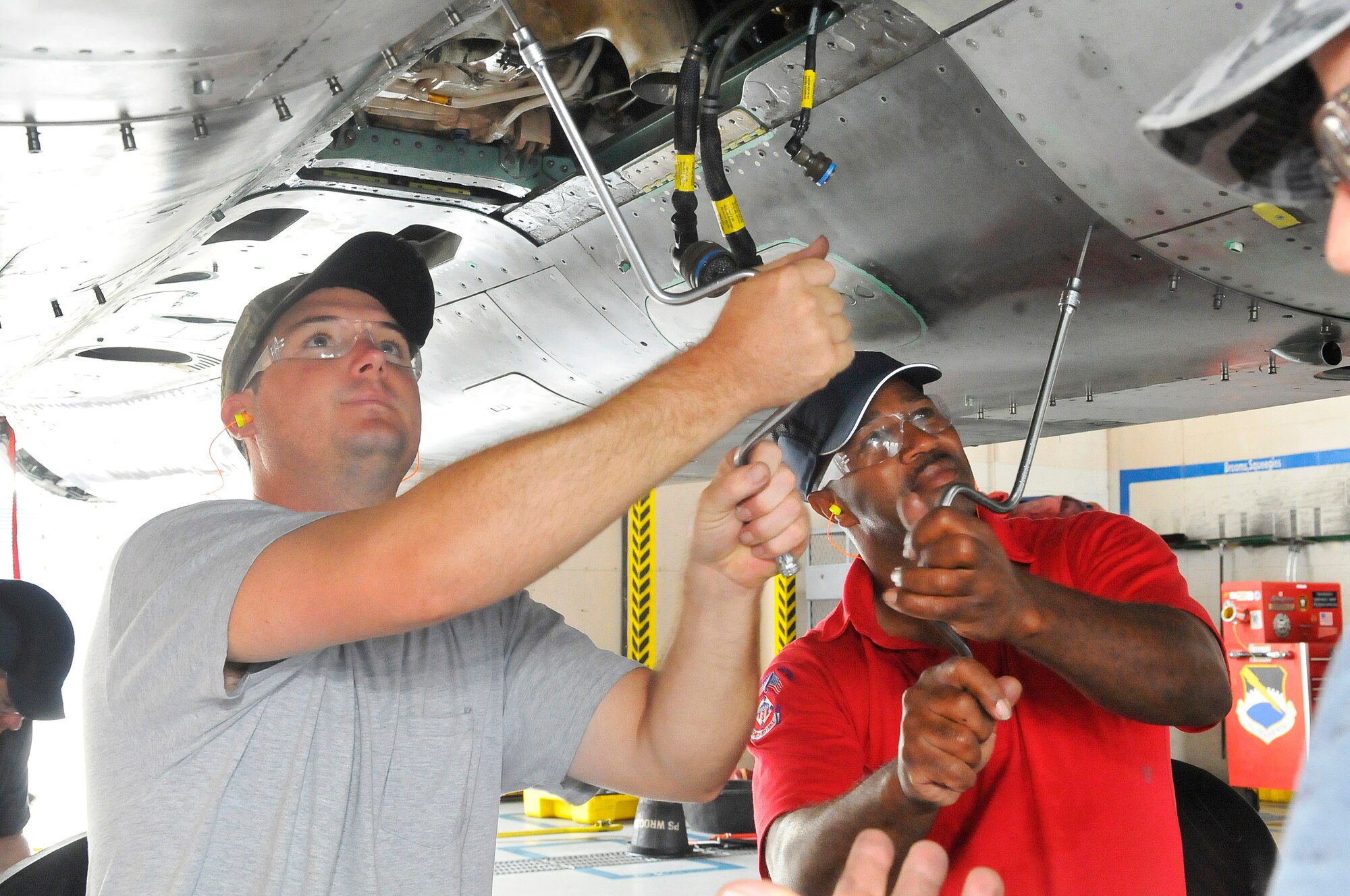 Mike Sheppard and John Davis, aircraft mechanics, remove a panel under an F-15 for an inspection at functional test.  F-15 Functional Test is the last stop for the aircraft going through maintenance. After it passes flight checks and a test flight, it is sent to be painted and then back to the unit to which it belongs.   (U. S. Air Force photo/Sue Sapp)