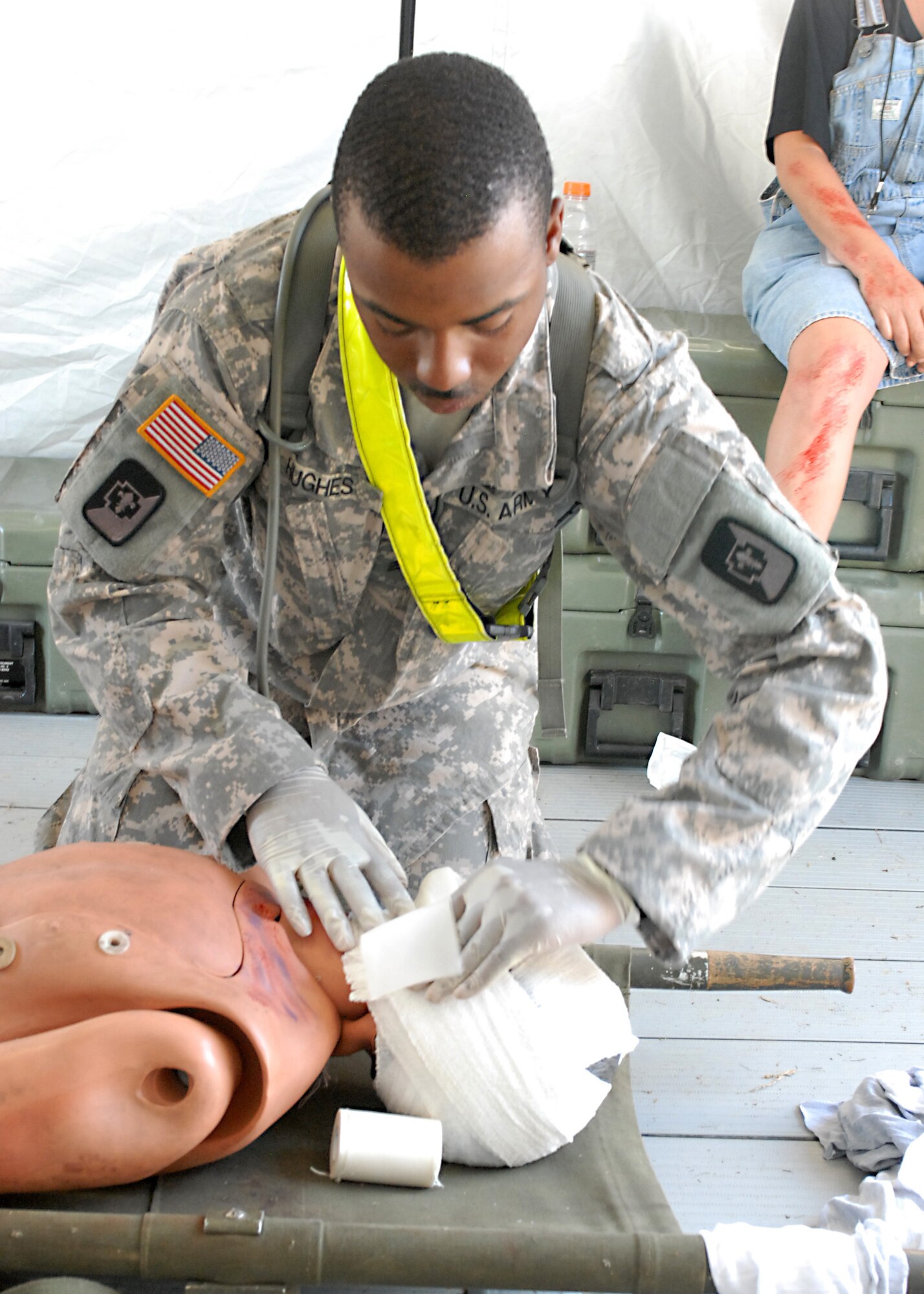 U.S. Army Sgt. Brandon Hughes, a combat medic assigned to the 547th Area Support Medical Company, 56th Multifunctional Medical Battalion, 62nd Medical Brigade out of Joint Base Lewis-McChord, Wash., bandages a mannequin posing as a injured civilian during a Vibrant Response 13 field training exercise at a soccer stadium located on the Muscatatuck Urban Training Center, Ind., July 26. Combat medics and military policemen supported Indiana civilian authorities by treating minor injuries during the exercise. (US Army photo by Sgt. Terence Ewings/ Released)