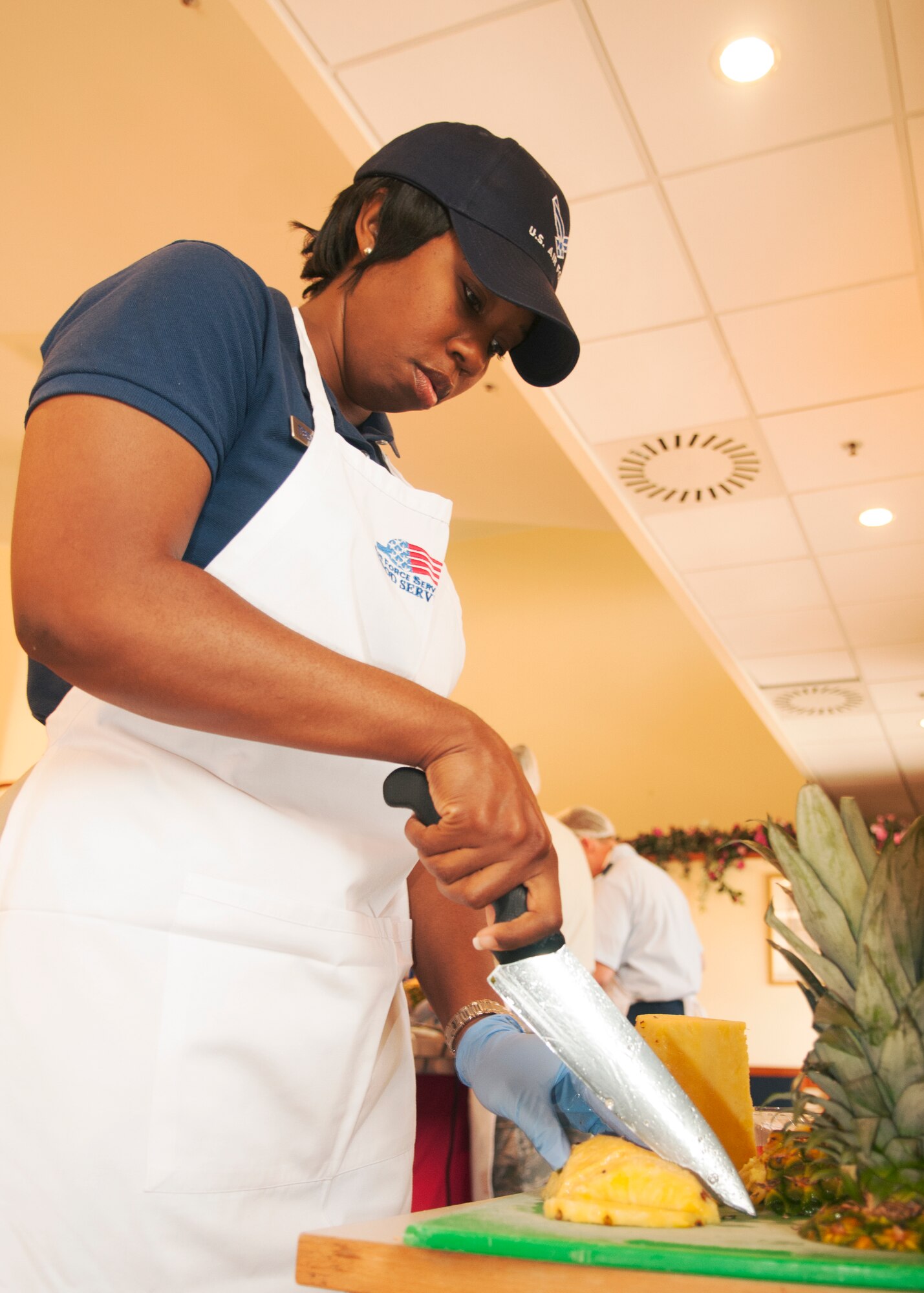 Tech. Sgt. Crystal Baranski, 31st Force Support Squadron fitness supervisor, cuts a pineapple in preparation for making a dessert during the quarterly Aviano Top Chef Competition at the La Dolce Vita dining facility August 6 at Aviano Air Base, Italy. The Company Grade Officer’s Council, the Top Chef overall winners, made a pineapple pork stir fry served with pita bread, fresh tomatoes and basil. For dessert, the team served judges a homemade apple cake. (U.S. Air Force photo/Airman 1st Class Briana Jones)