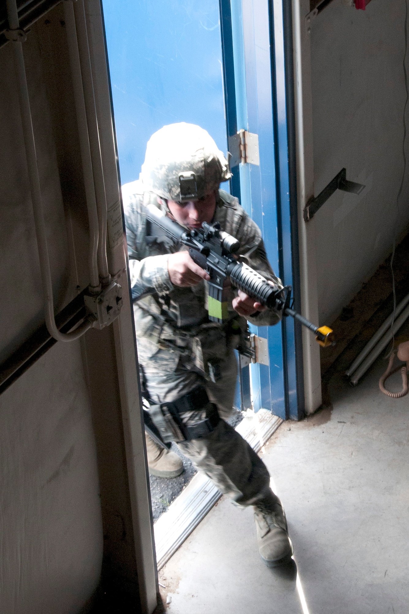 Senior Airman Steven Nunez storms through a warehouse door during an active shooter exercise at the 162nd Fighter Wing in Tucson Ariz. Nunez is from the Security Forces Squadron, whose members were being trained and evaluated in response to a simulated active shooter threat.  (U.S. Air Force photo/Master Sgt. David Neve)