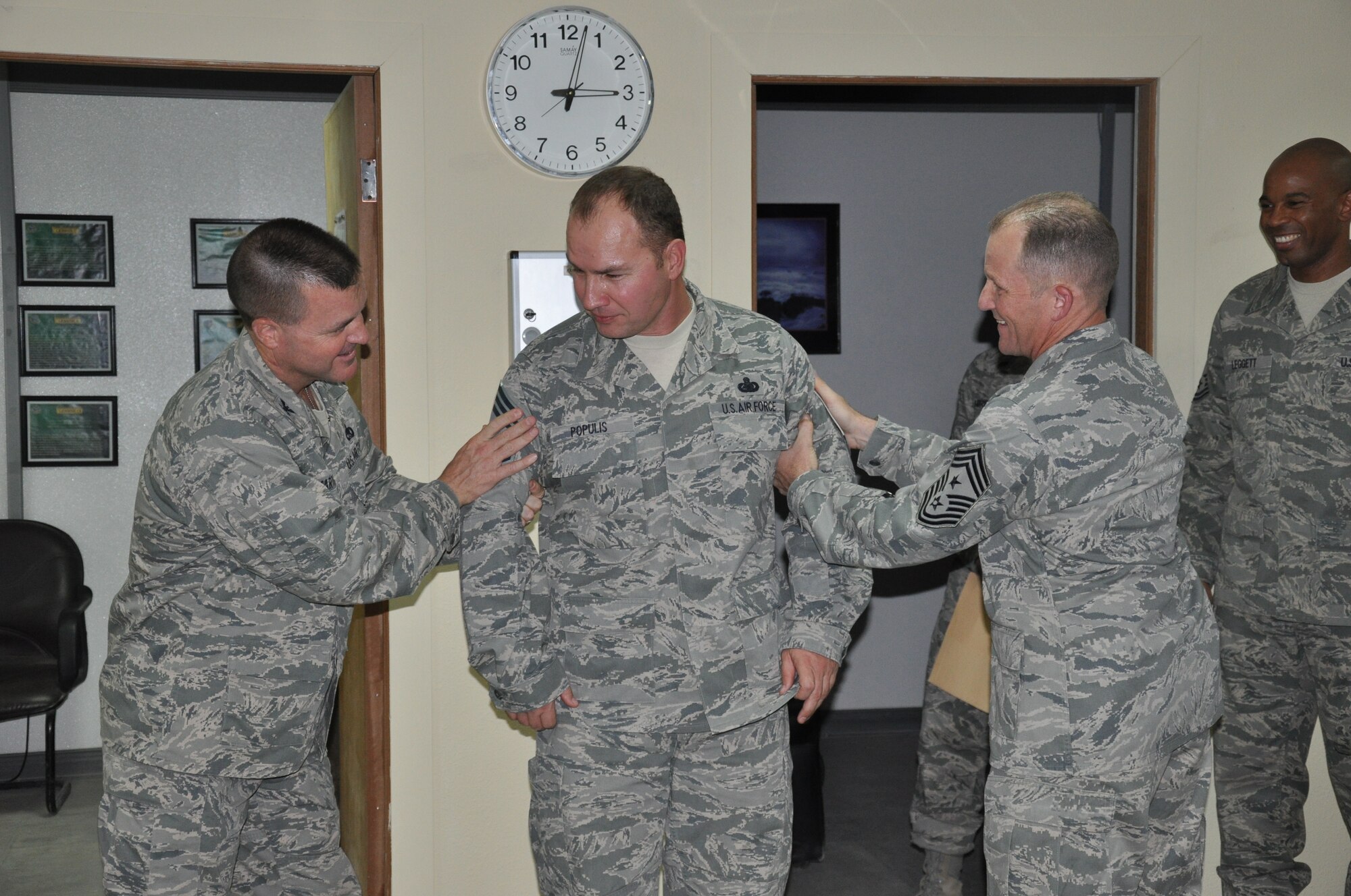 SOUTHWEST ASIA - Colonel Joseph Martin and Chief Master Sgt. Dennis Daubert prepare to "tack" chief stripes on Senior Master Sgt. James Populis to recognize his promotion to the rank of chief master sergeant here Aug. 9. The chief-select from the 386th Expeditionary Logistics Readiness Squadron was promoted through the supplemental promotion system. Martin is the 386th Expeditionary Mission Support Group commander and Daubert is the 386th Air Expeditionary Wing command chief master sergeant. (U.S. Air Force photo/Master Sgt. Kristina Barrett)