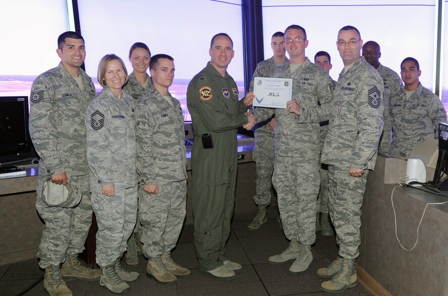Senior Airman Joshua Smith, 47th Operations Support Squadron air traffic control journeyman, poses with Col. Tom Murphy, 47th Flying Training Wing commander, and Chief Master Sgt. Garry Berry, 47th FTW command chief, after being presented the XLer of the week award at Laughlin Air Force Base, Texas, July 25, 2012. The XLer is a weekly award chosen by wing leadership and given to those who consistently make outstanding contributions to Laughlin and their unit. (U.S. Air Force photo/Jose Mendoza)