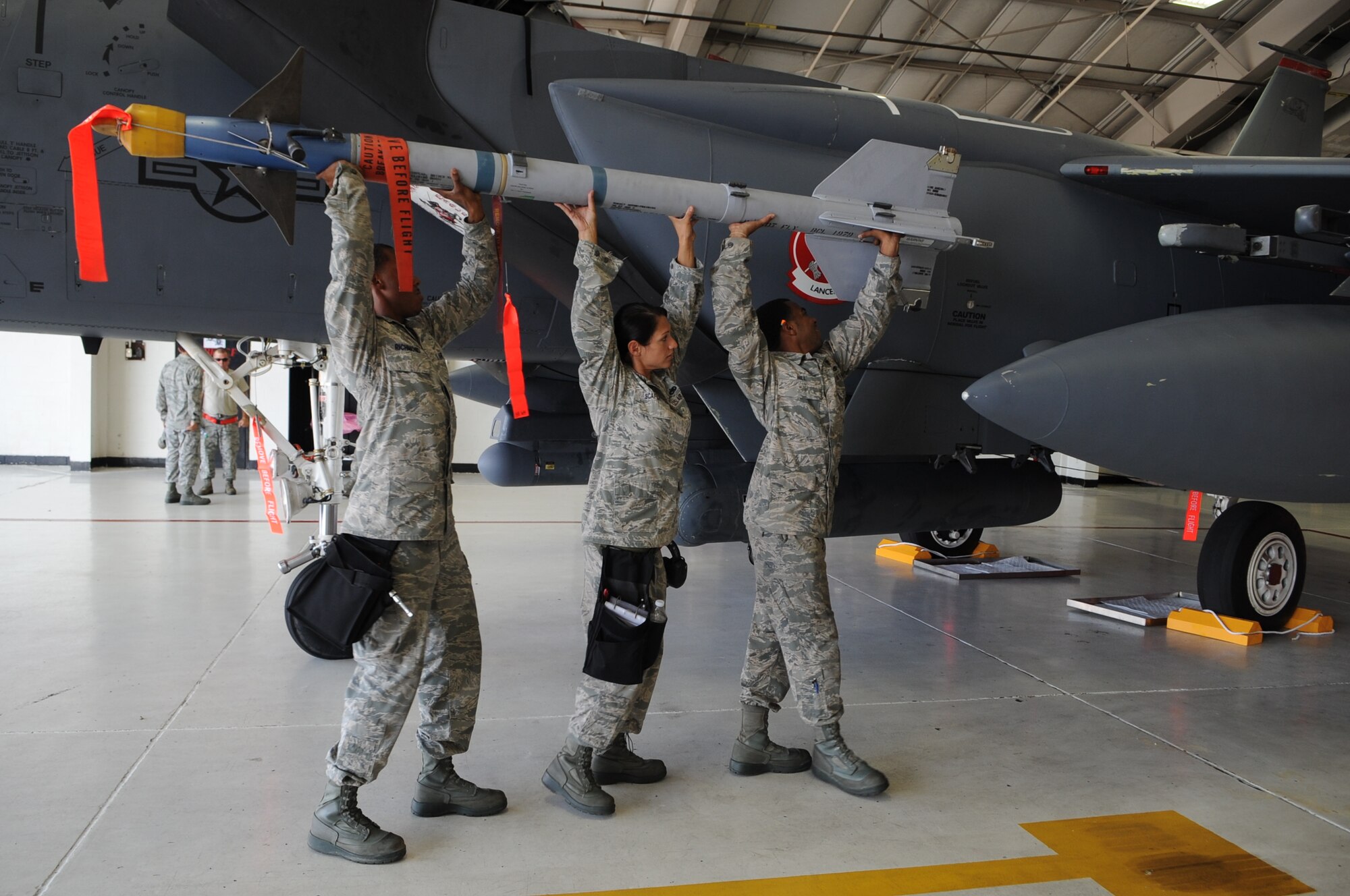 A weapons load crew of U.S. Air Force Airmen from the 333rd Aircraft Maintenance Unit attempt to load an Aim-9 Sidewinder missile onto an F-15E Strike Eagle on Seymour Johnson Air Force Base, N.C., Aug. 2, 2012. The aircraft was mocked up in full battle ensemble to honor Dyrk Burcie, a 4-year old living with terminal, stage four, pediatric liver cancer. (U.S. Air Force photo/Airman 1st Class Aubrey Robinson/Released)