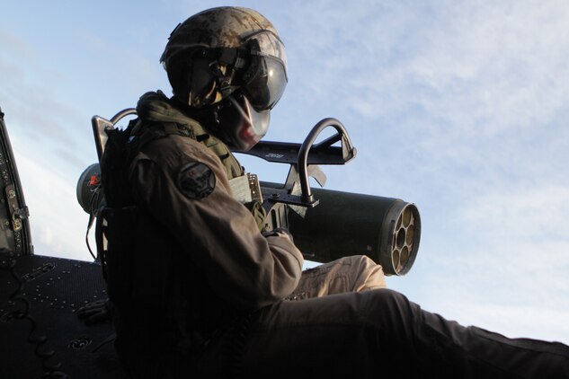 Lance Cpl. Michael J. Costa, Marine Light Attack Helicopter Squadron 269 crew chief sits on the edge of  the UH-1Y Huey he is flying in watching to ensure that it is clear of any obstacles while the Marines on board practice tactical flying and confined area landings to gain proficiency with the latest model of the Huey, Aug. 9.