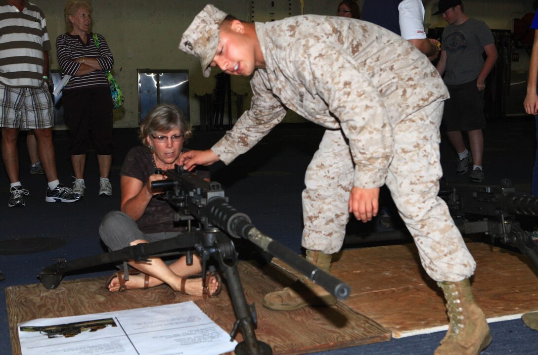 Cpl. Sean Chilson, a heavy equipment operator with Combat Logistics Regiment 27, 2nd Marine Logistics Group, assists a visitor aboard the USS San Antonio with the Browning M2 .50 Caliber Machine Gun during Maine’s 2012 Lobster Festival in Rockland, Aug. 3. The ship dropped its ramp in order to show the American people some of its capabilities. (Photo by Lance Cpl. Paul Peterson)