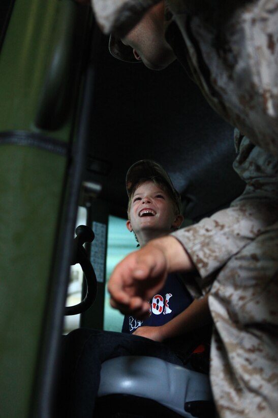 A Marine from Combat Logistics Regiment 27, 2nd Marine Logistics group shows a young visitor to the USS San Antonio how to operate a multi-purpose tractor during Maine’s 2012 Lobster Festival in Rockland, Aug. 3. The loud rumbling of the vehicle’s engine joined that of other equipment as Marines and sailors aboard the vessel guided visitors though the vessel’s various displays. (Photo by Lance Cpl. Paul Peterson)