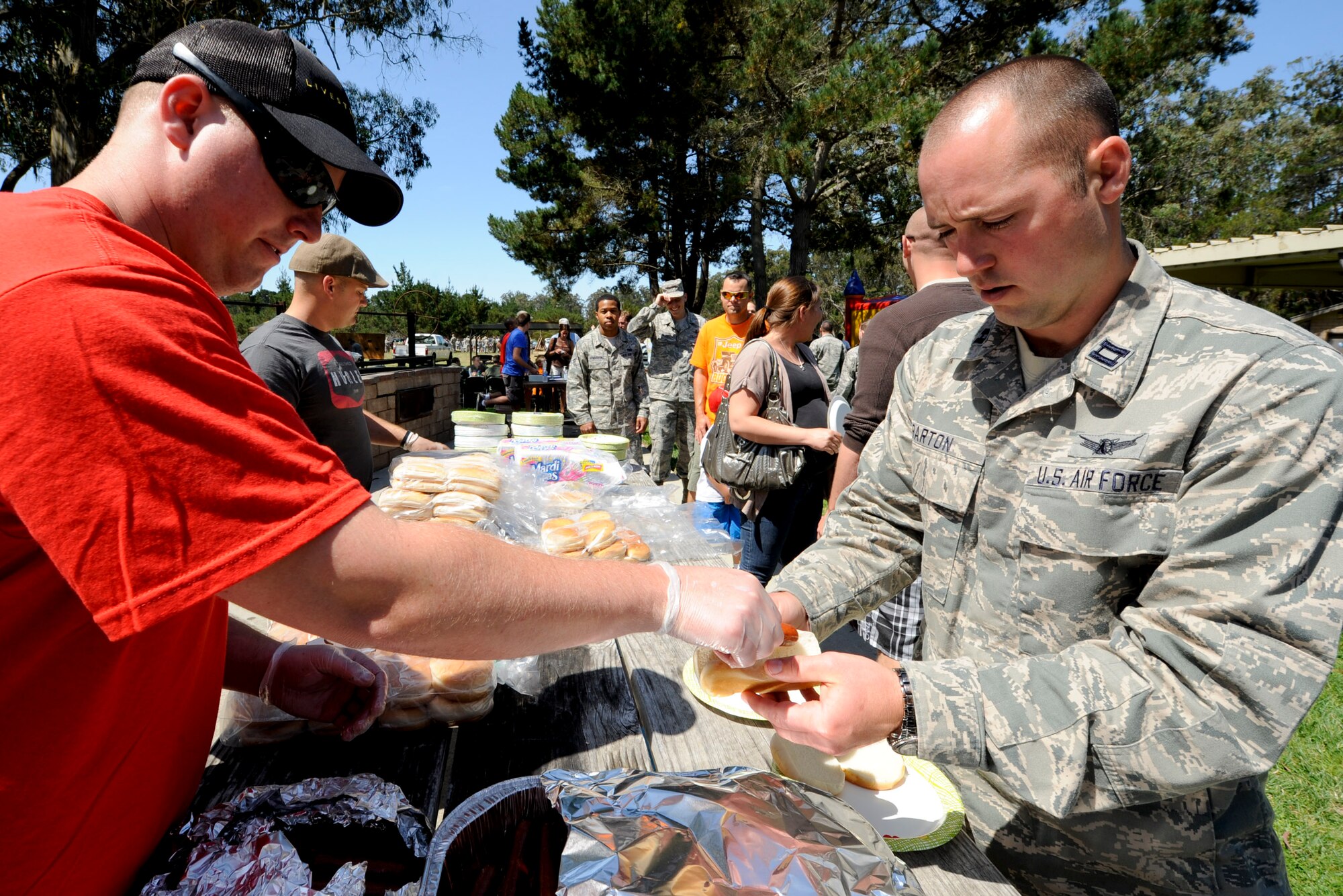 VANDENBERG AIR FORCE BASE, Calif. -- 2nd Lt. Mason Armstrong, a 532nd Training Squadron member, serves a hotdog to Capt. Nick Barton, a 533rd Training Squadron member, during the 24th Annual Texas Blowout event at Cocheo Park here Friday, August 10, 2012. The 392d Training Squadron hosted the event to help support families and bring camaraderie to the Vandenberg community by providing attractions including a bounce house, a car show, pin the tail on the donkey and a cow pie tossing competition.  (U.S. Air Force photo/Staff Sgt. Levi Riendeau)