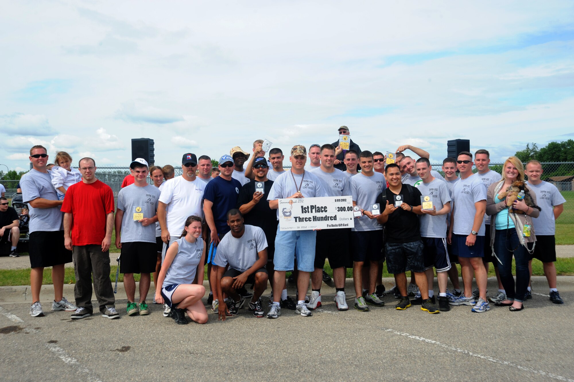 Members of the 319th Operations Support Squadron receive a $300 check for winning first place Aug. 9 during Summer Bash 2012, on Grand Forks Air Force Base, N.D Summer Bash is an annual event designed to boost morale and increase esprit de corps. The 319th Operations Support Squadron placed first overall, with the 319th Civil Engineer Squadron placing second and the 69th Reconnaissance Group placing third. (U.S. Air Force photo/Airman 1st Class Xavier Navarro)