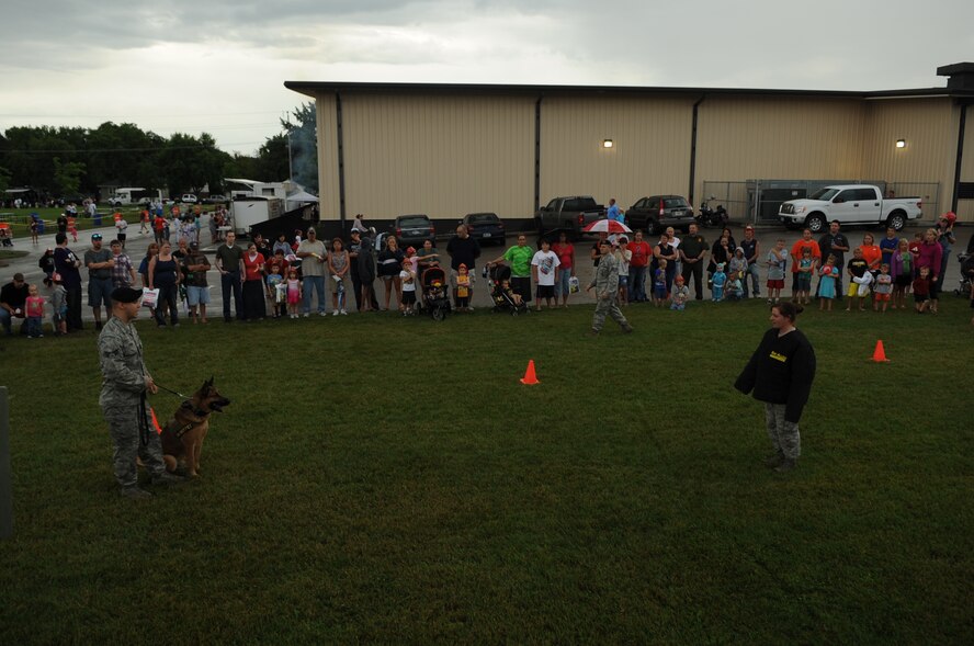 Senior Airman Brett Silmon and his military working dog and Staff Sgt. Angela Lowe, 319th Security Forces Squadron, perform a demonstration of the capabilities of the MWD to a crowd during the National Night Out Picnic in Grand Forks, N.D., on Aug 7, 2012. National Night Out picnic is an event held to inform the community about law enforcement and fire safety. Events also included a weapons display and a simulated house fire. (U.S. Air Force/ Staff Sgt. Amanda N. Grabiec)
