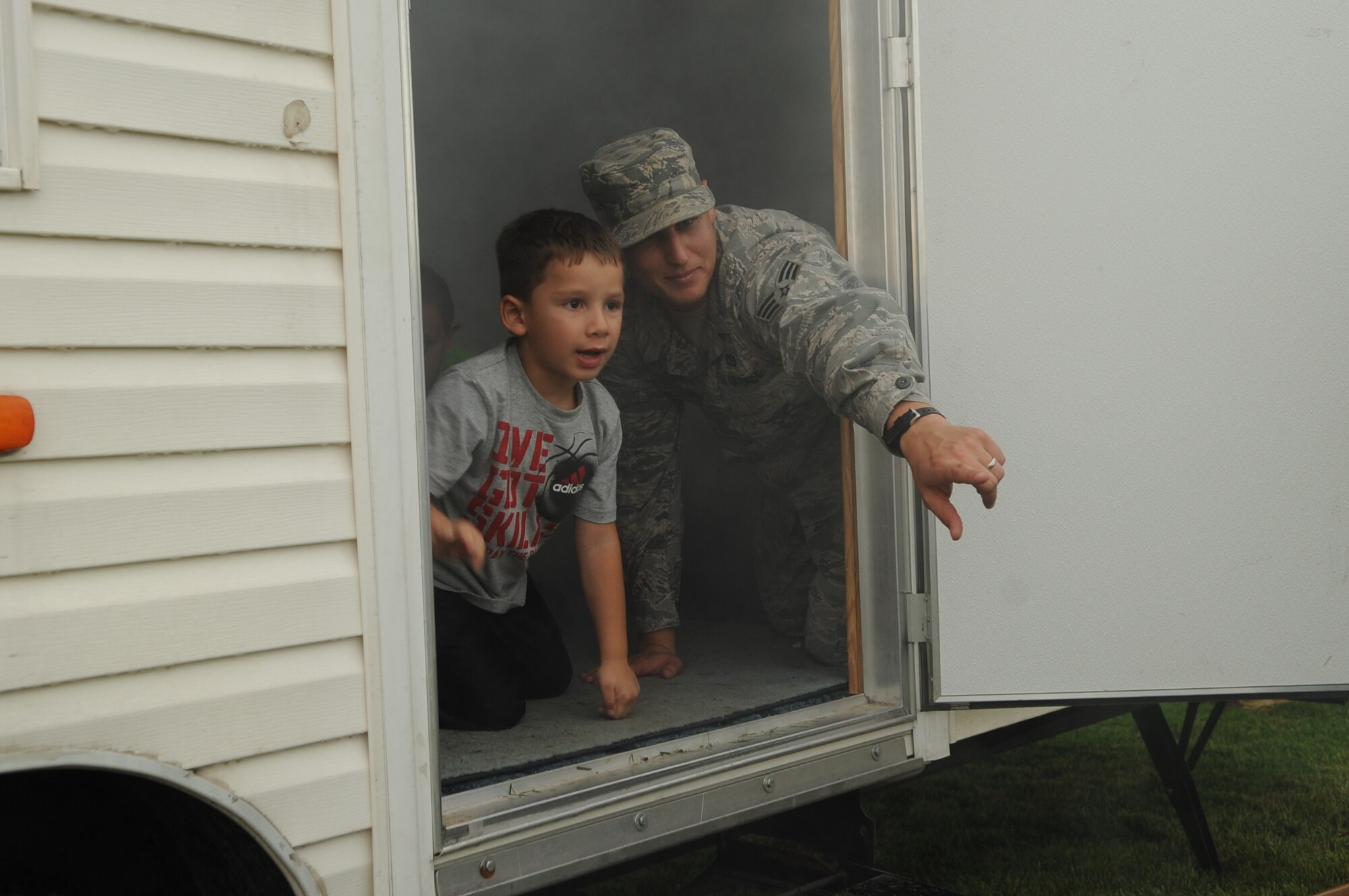 Senior Airman Shane Holland, 319th Civil Engineer Squadron, directs a child where to go during a simulated house fire during the National Night Out Picnic in Grand Forks, N.D., on Aug 7, 2012. National Night Out picnic is an event held to inform the community about law enforcement and fire safety. Events also included a military working dog demonstration and weapons display. (U.S. Air Force/ Staff Sgt. Amanda N. Grabiec)
