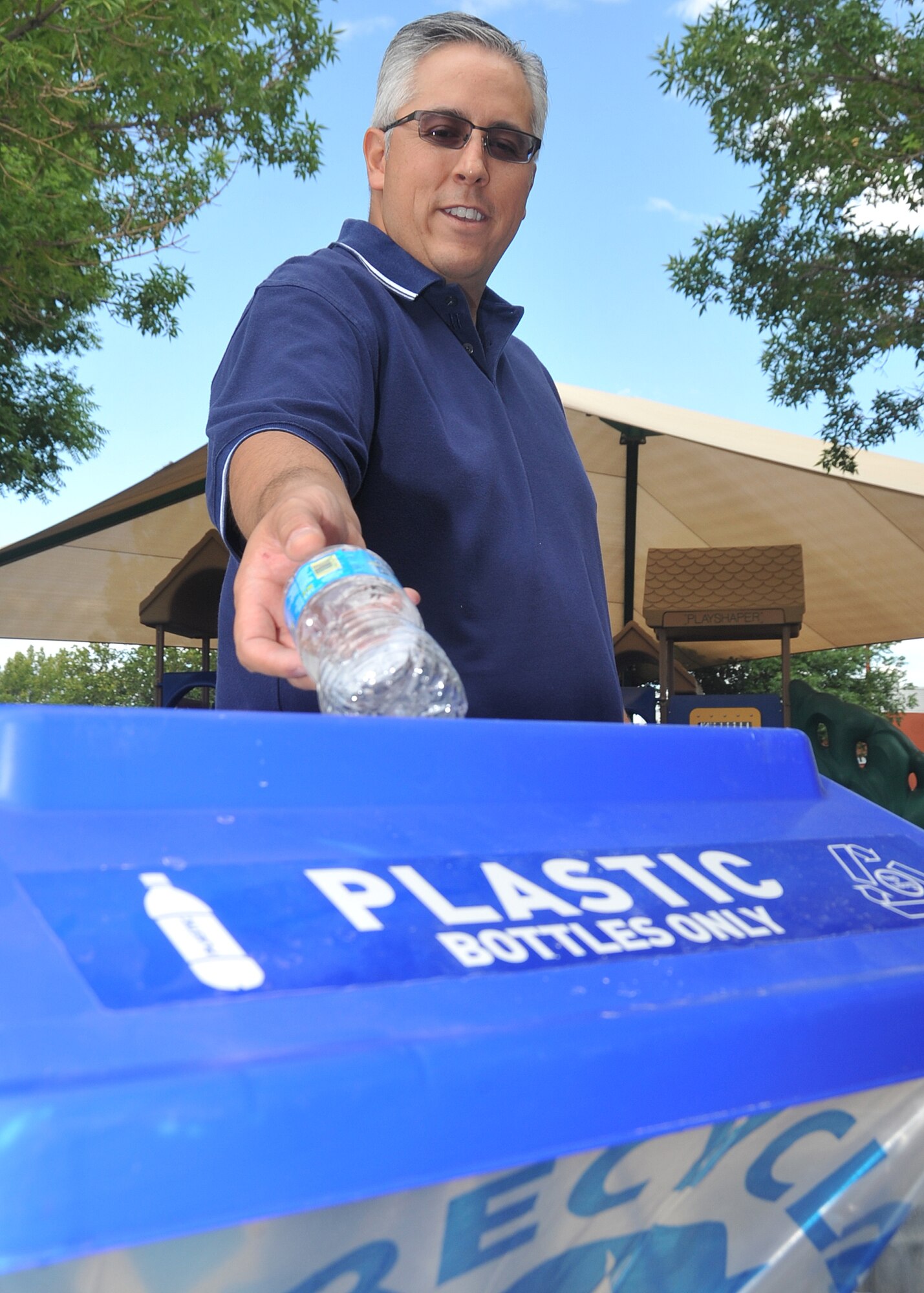 KIRTLAND AFB, N.M. – Chuck Cordova, civil engineering asset optimization technician, uses a portable recycling container August 8 at Kirtland AFB. (Photo by Todd Berenger)