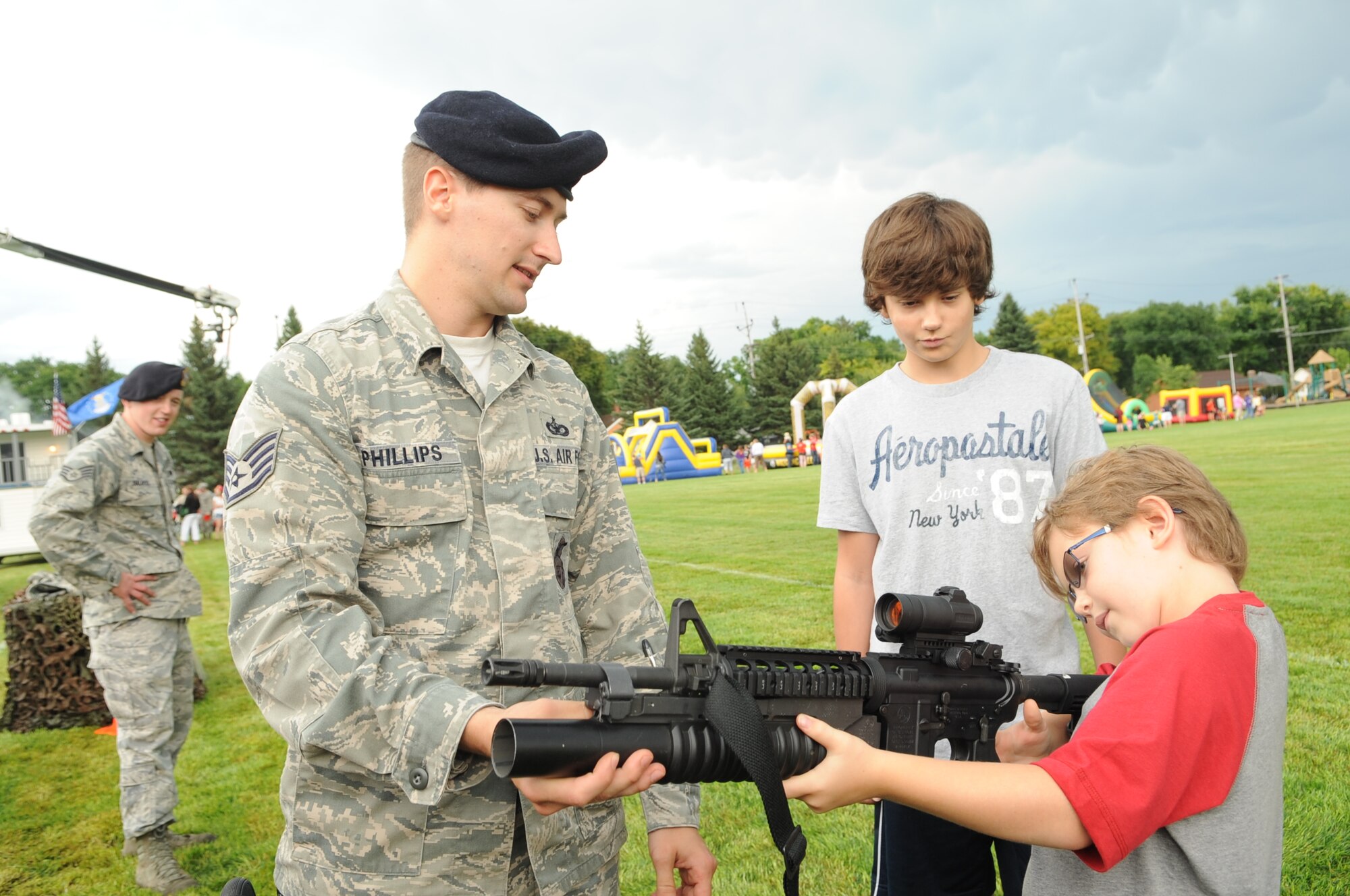 Staff Sgt. Christopher Phillips, 319th Security Forces Squadron, shows  an M4 with grenade launcher to Grant Rothenberger, 8, at the National Night Out in Grand Forks, N.D., on Aug 7, 2012. The National Night Out picnic is an event held to inform the community about law enforcement and fire safety. Events included a military working dog demonstration, weapons display, and a simulated house fire. (U.S. Air Force/ Staff Sgt. Amanda N. Grabiec)