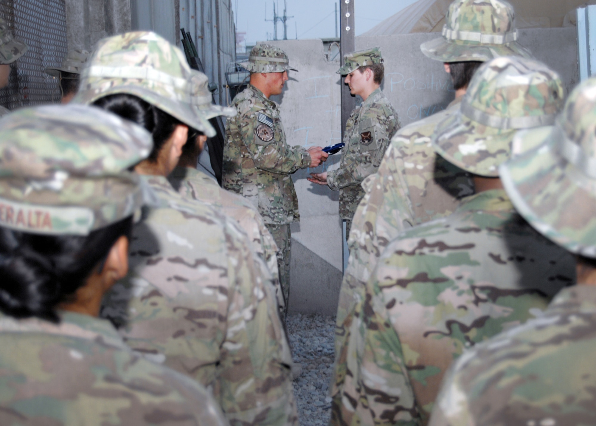 Staff Sgt. Michael Newman presents the flag to Staff Sgt. Kristy Wolfmayer, marking the end of retreat at Kandhar Airfield, Afghanistan,  Aug. 4, 2012. Wolfmayer's father, John Woflmayer from Califon, N.J., designed, built and shipped the flagpole to Kandahar Airfield.  Newman and Wolfmayer are with the 651st Expeditionary Aeromedical Evacuation Squadron. (U.S. Air Force photo/Master Sgt. Russell Martin)