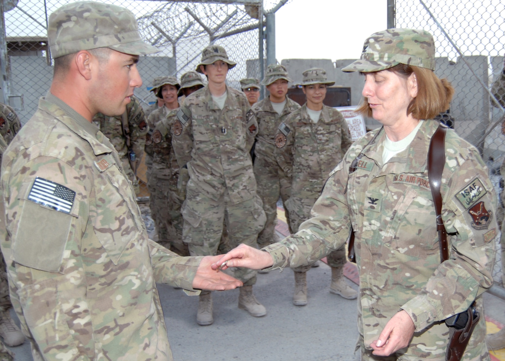 Airman 1st Class Allen Holder, receives a coin from Col. Elizabeth Harrell. Holder volunteered his time and brought over an auger drill to help make way for the new flagpole. Holder is with the 451st Expeditionary Civil Engineer Squadron and deployed from Nellis Air Force Base, Nev., and Harrell 651st Expeditionary Aeromedical Evacuation Squadron commander and deployed from Scott AFB, Ill. (U.S. Air Force photo/Master Sgt. Russell Martin)