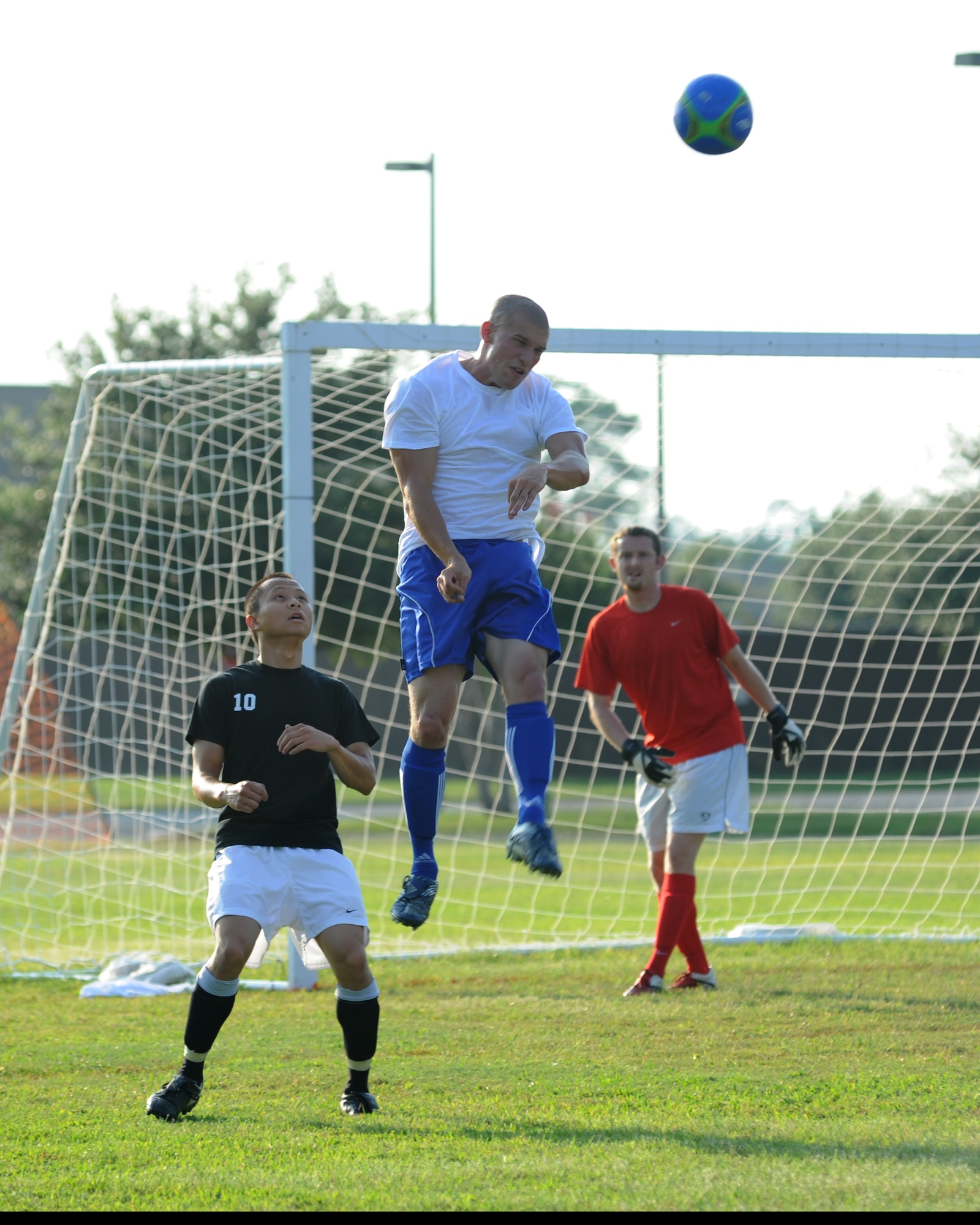 Quang Tran, 85th Engineering Installation Squadron, holds his place as Steve Bordelon, 334th Training Squadron, leaps into the air for a header with the Gator’s goalie standing by during an intramural soccer game August 7, 2012, at Keesler Air Force Base, Miss.  The Gators defeated the 85th 6-2.  (U.S. Air Force photo by Kemberly Groue)