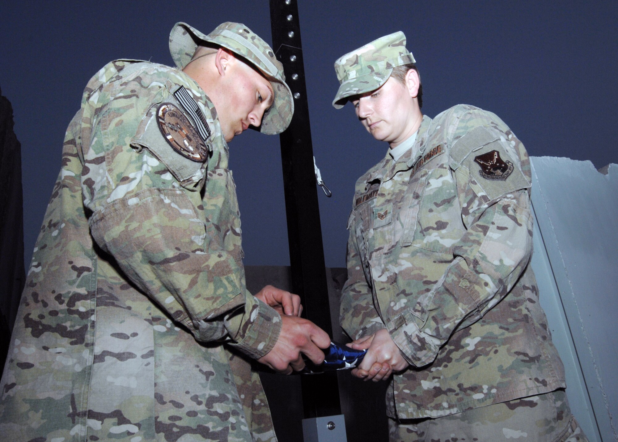 Staff Sgt. Michael Newman and Staff Sgt. Kristy Wolfmayer, both deployed from Travis Air Force Base, Calif., fold the flag during a retreat ceremony at Kandahar Airfield, Afghanistan,  Aug 4, 2012. Newman and Wolfmayer are assigned to the 651st Expeditionary Aeromedical Evacuation Squadron. (U.S. Air Force photo/Master Sgt. Russell )